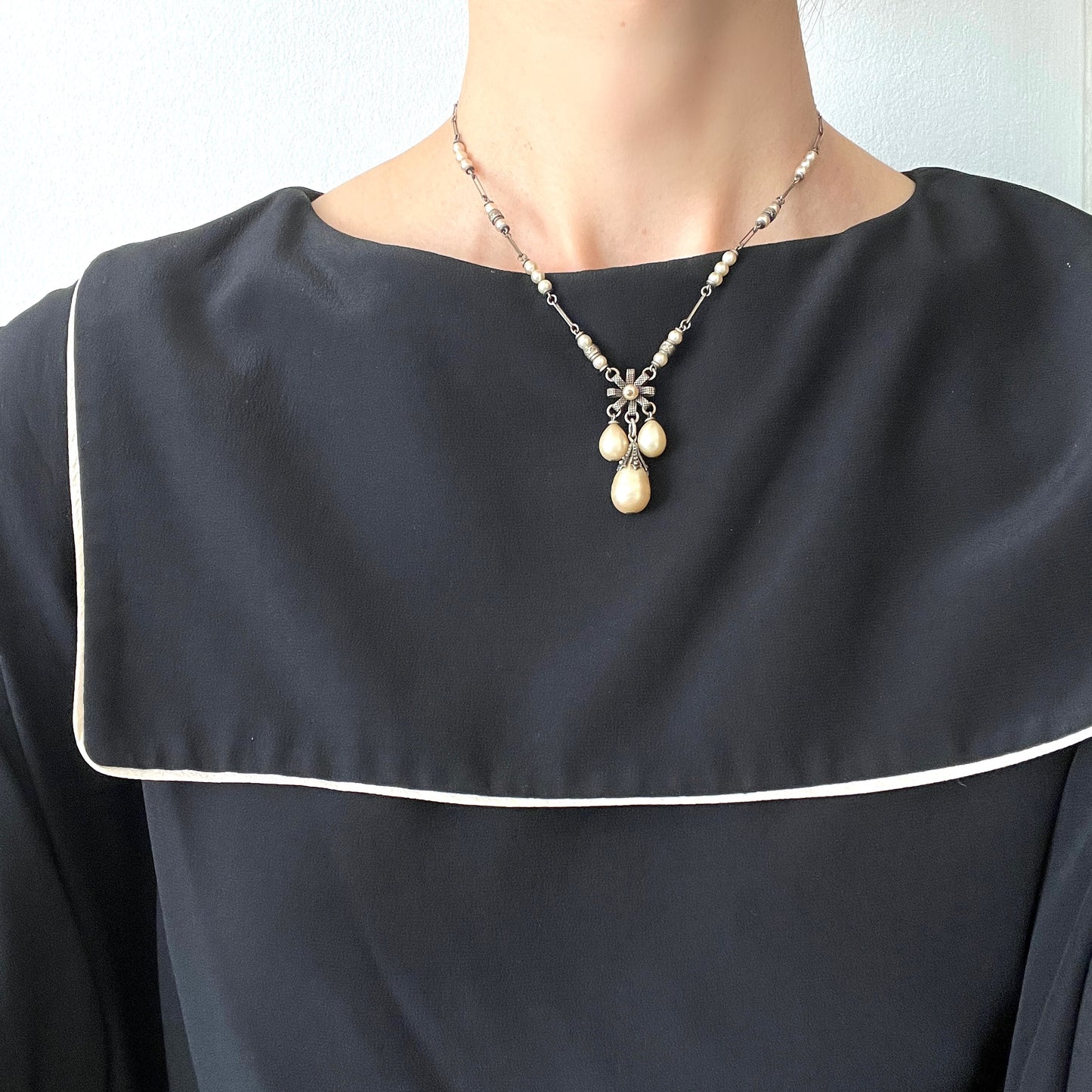 A necklace featuring metal flowers reminiscent of daisies, from which dangle chunky handmade teardrop glass pearls. デイジーのようなメタルのお花に、ゴロンとしたハンドメイドのティアドロップグラスパールがさがったネックレス。