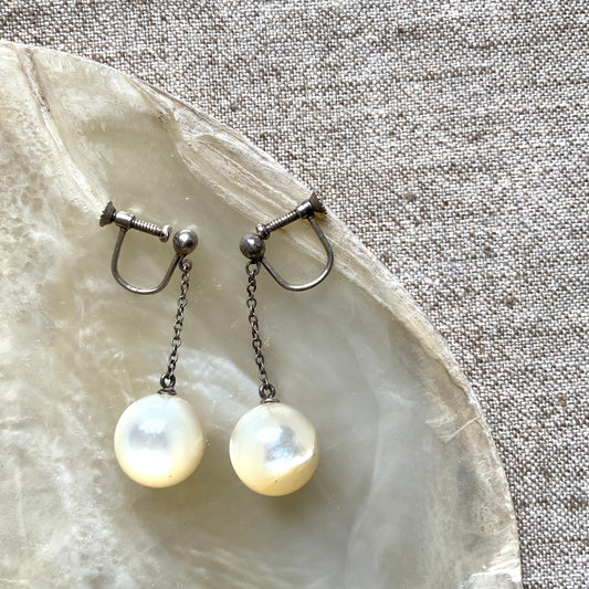 Silver screw-back earrings with dangling mother-of-pearl ball beads. マザーオブパールのボールビーズがゆれる、シルバーのスクリューバックイヤリング。