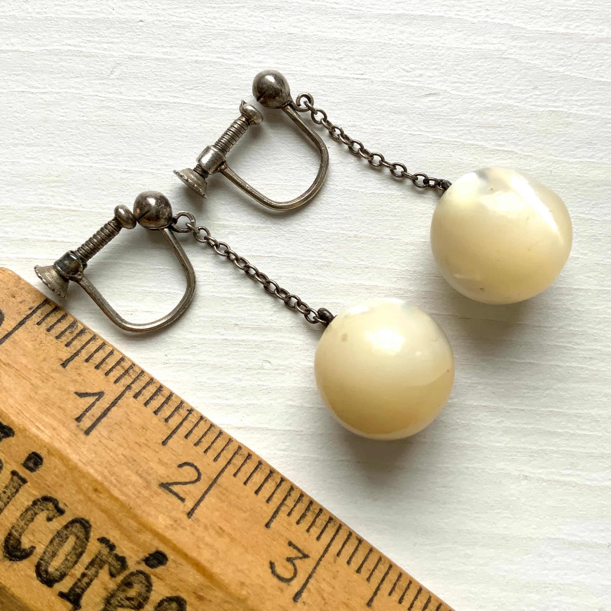 Silver screw-back earrings with dangling mother-of-pearl ball beads. マザーオブパールのボールビーズがゆれる、シルバーのスクリューバックイヤリング。