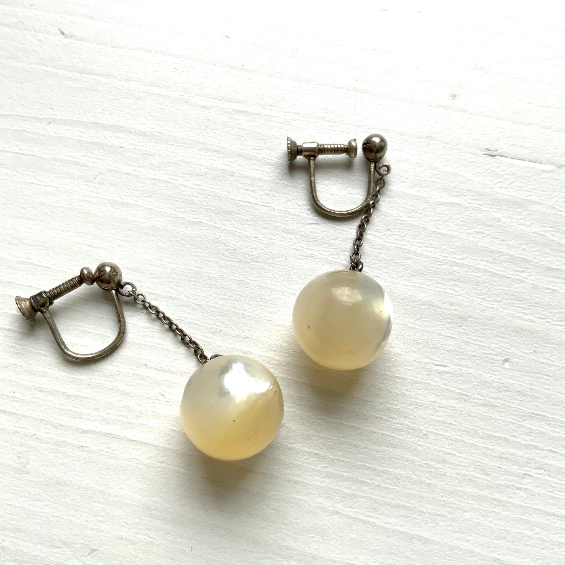 Silver screw-back earrings with dangling mother-of-pearl ball beads. マザーオブパールのボールビーズがゆれる、シルバーのスクリューバックイヤリング。