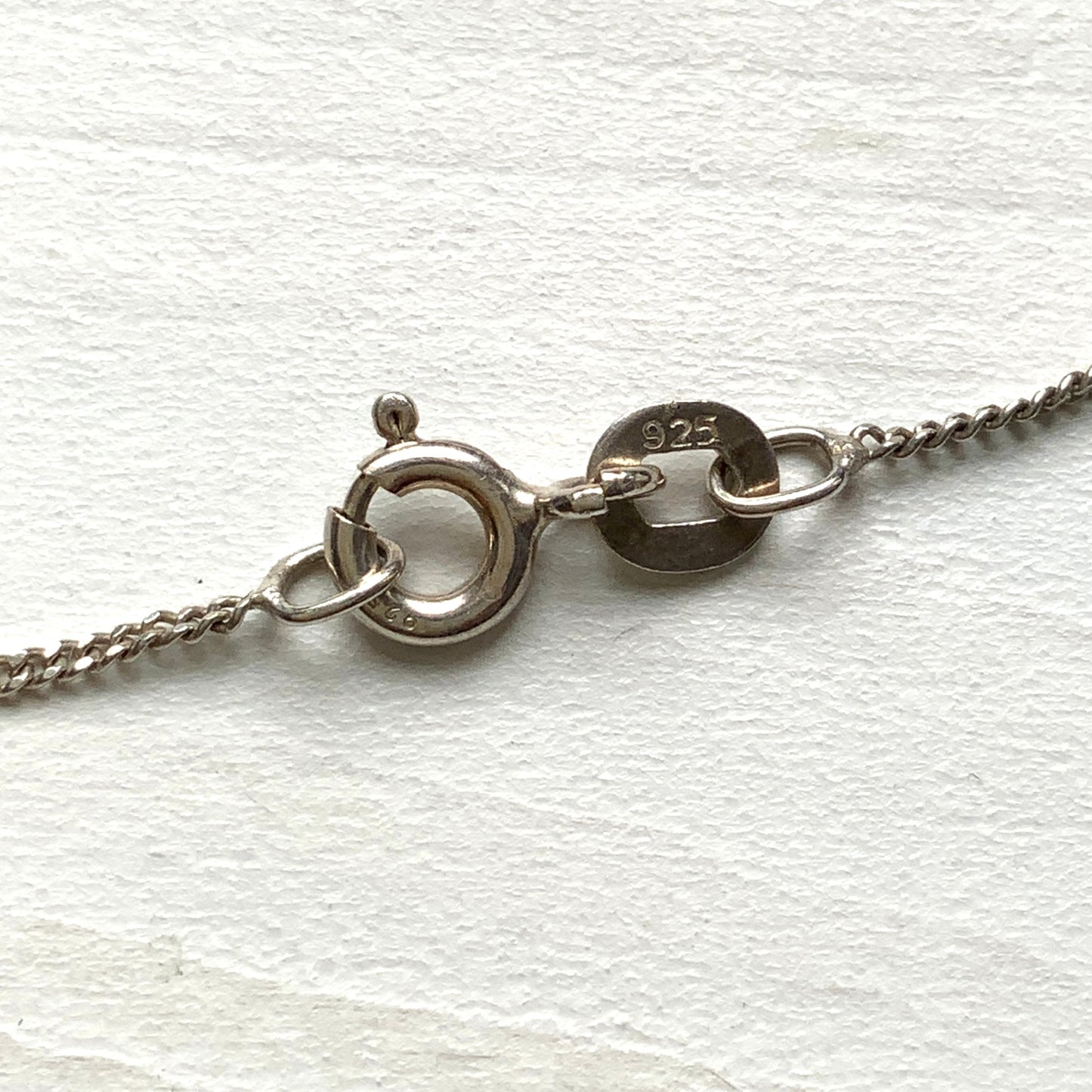 A silver necklace featuring onyx-like black glass paired with a teardrop of smooth, lustrous mother of pearl. オニキスのような艶をもつブラックグラスと、滑らかな光沢が美しいマザーオブパールのティアドロップを組み合わせた、シルバーネックレス。