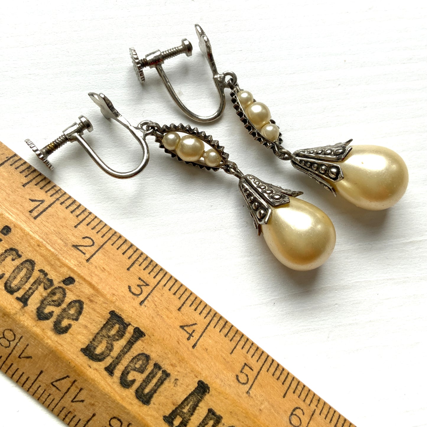 Screw-back earrings featuring teardrop glass pearls that gently dangle. ティアドロップのグラスパールが揺れるスクリューバックイヤリング。