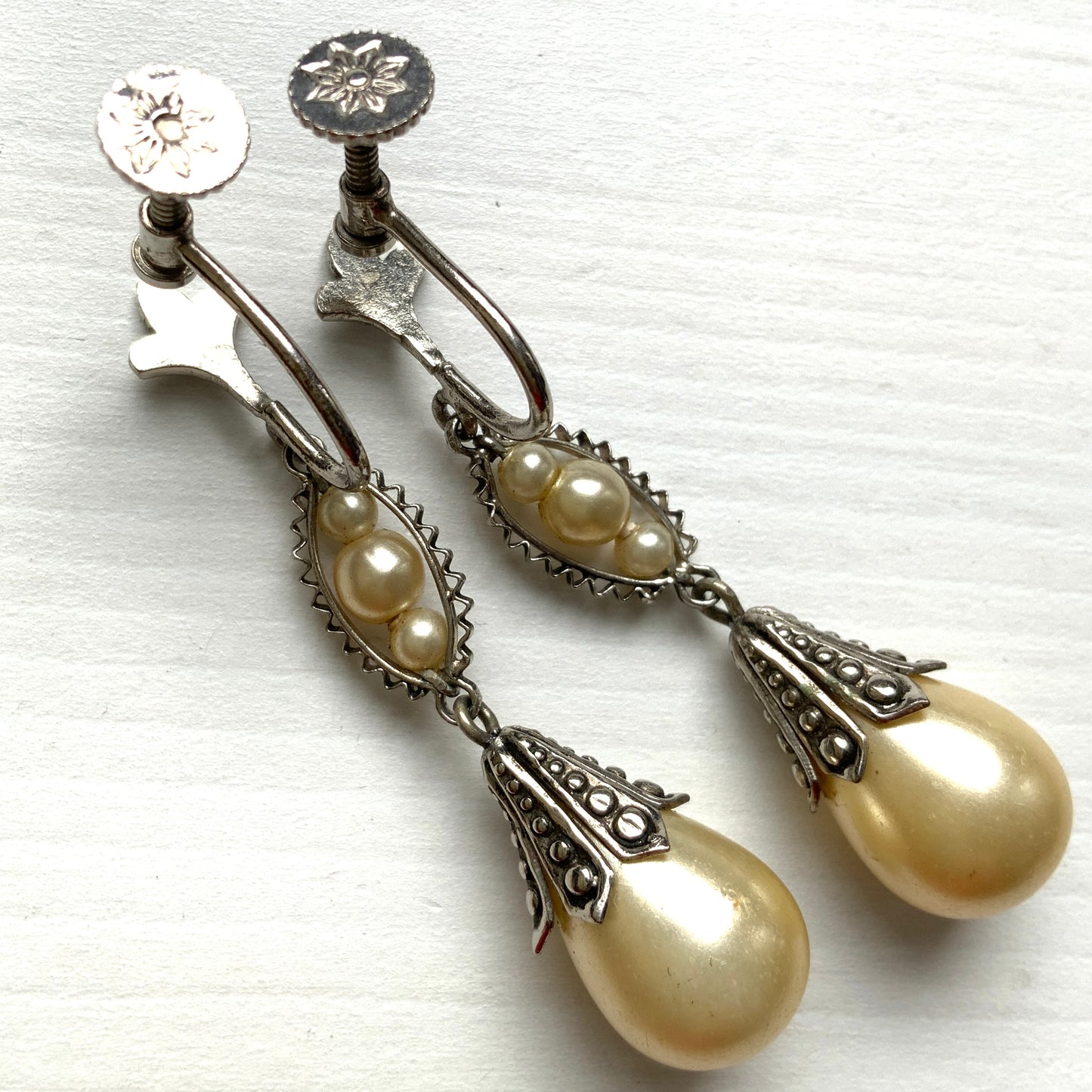 Screw-back earrings featuring teardrop glass pearls that gently dangle. ティアドロップのグラスパールが揺れるスクリューバックイヤリング。