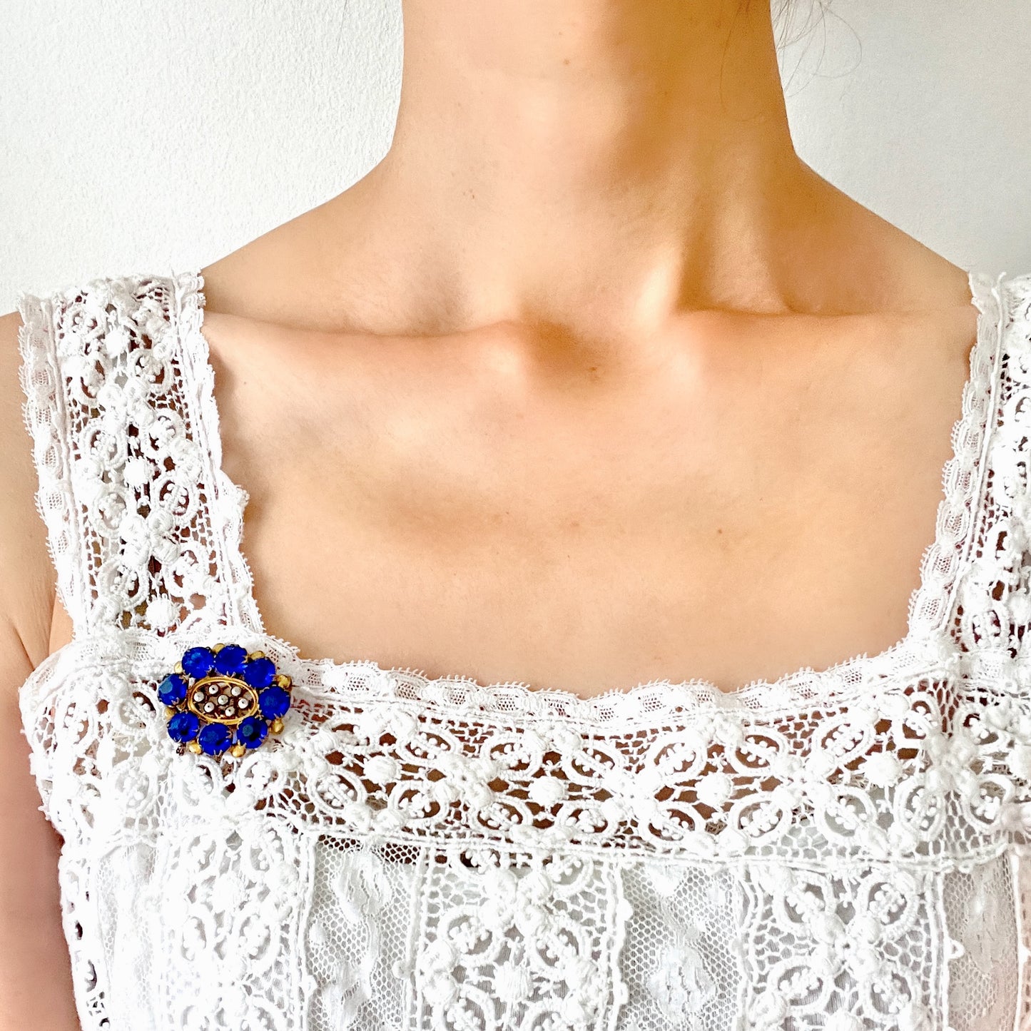 A brooch featuring a vivid, ultramarine blue glass stone that draws the eye with its deep, striking colour. ウルトラマリンのような深く鮮やかなブルーが印象的な、グラスストーンのブローチ。