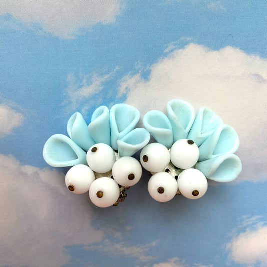 These clip-on earrings feature petal-like pastel blue glass beads paired with white milk glass beads that resemble berries. 花びらのような淡いパステルブルーのグラスビーズに、白い実のようなミルクグラスビーズがついたクリップイヤリング。