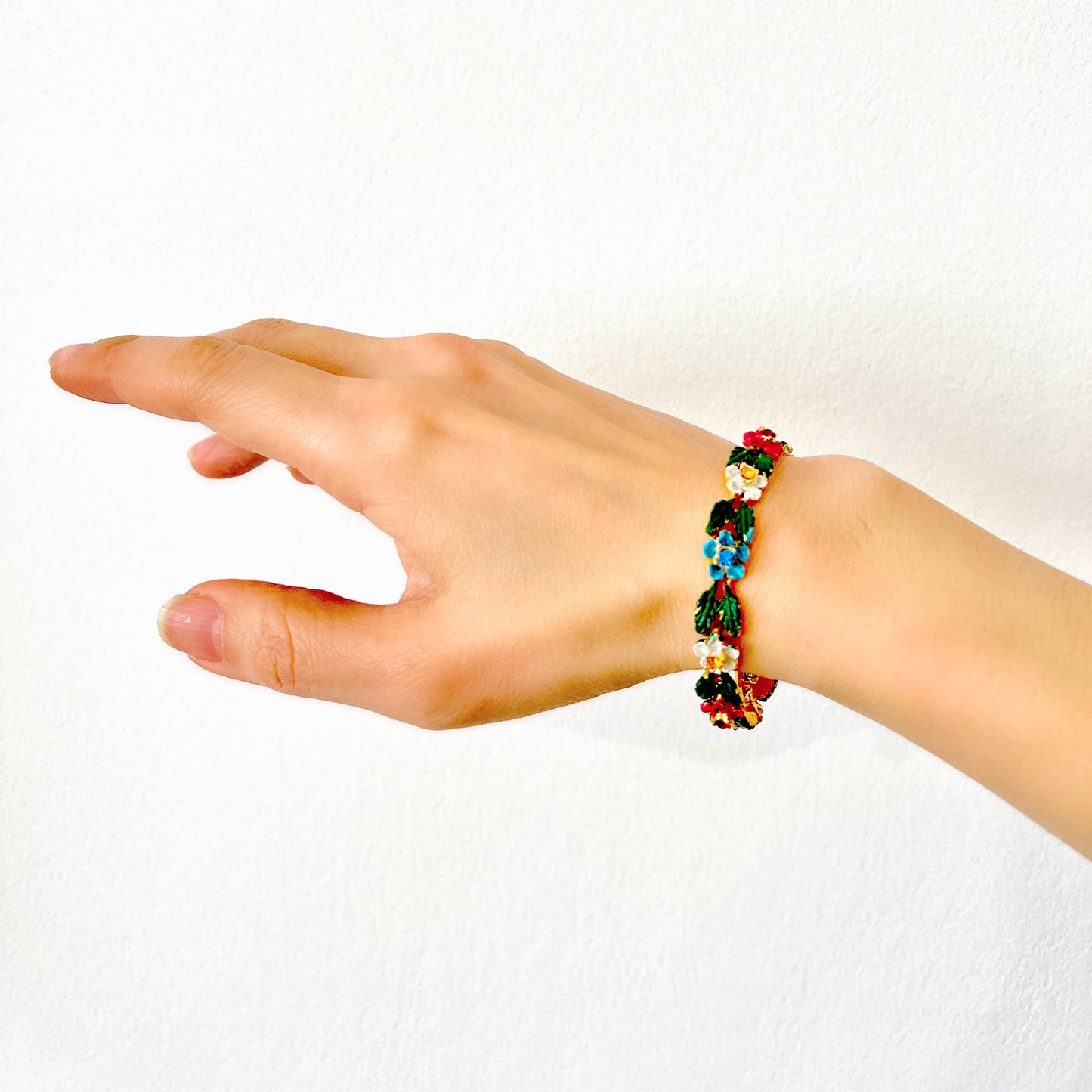 A delicate enamel bracelet adorned with rows of pink, pale blue and white flowers. ピンク、水色、白のお花が並んだエナメルのブレスレット。
