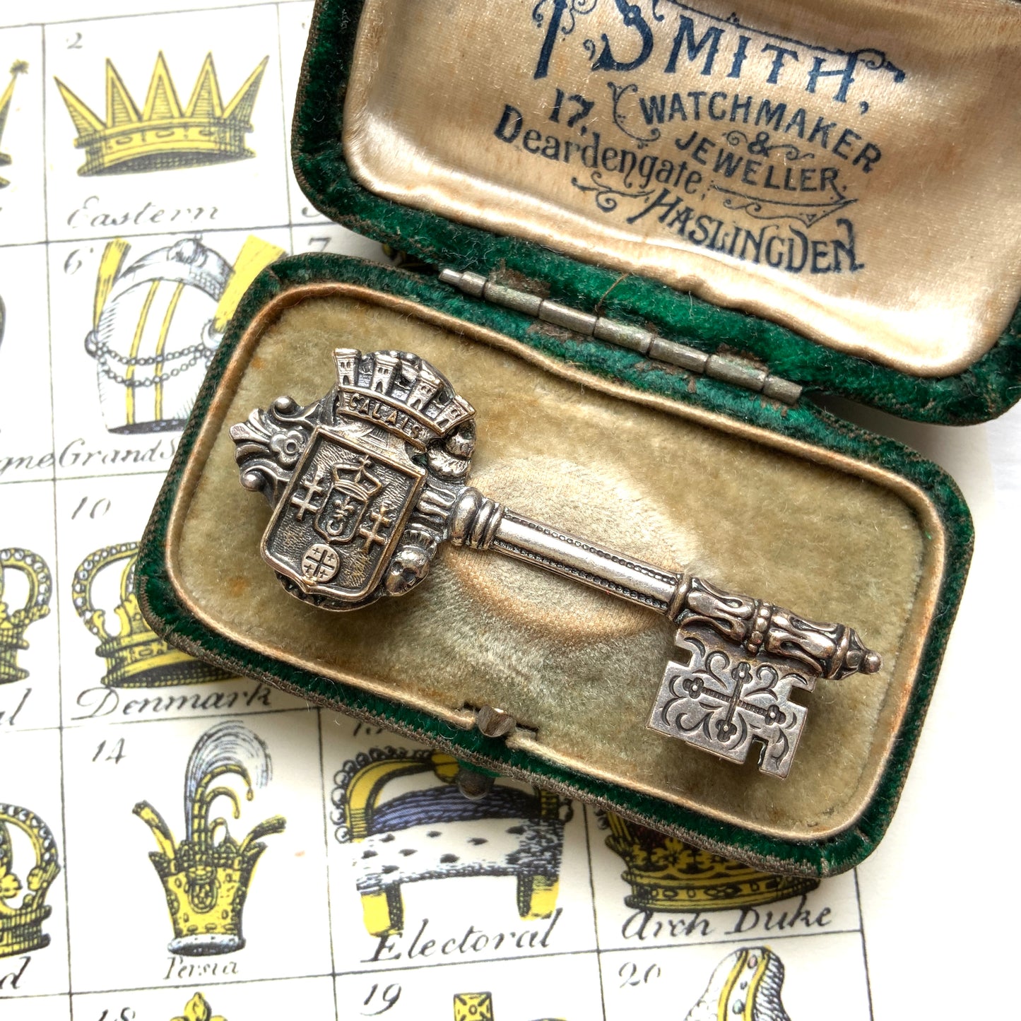 A decorative vintage key brooch featuring a crown and crest motif in a beautifully classical design. 王冠と紋章のモチーフ、クラシカルでデコラティブなデザインが素敵な鍵ブローチ。