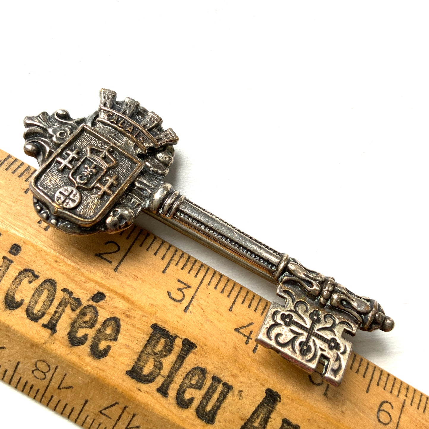 A decorative vintage key brooch featuring a crown and crest motif in a beautifully classical design. 王冠と紋章のモチーフ、クラシカルでデコラティブなデザインが素敵な鍵ブローチ。