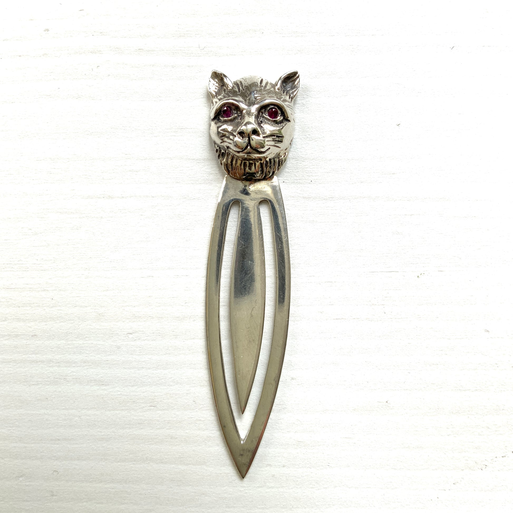 A cute cat's head peeks out from your book — a silver bookmark with a touch of charm.  かわいい猫の頭が本からのぞく、シルバー製のブックマーク。