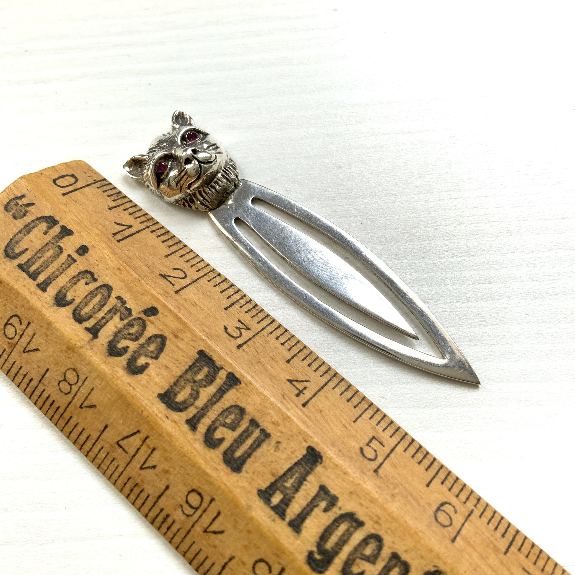 A cute cat's head peeks out from your book — a silver bookmark with a touch of charm.  かわいい猫の頭が本からのぞく、シルバー製のブックマーク。