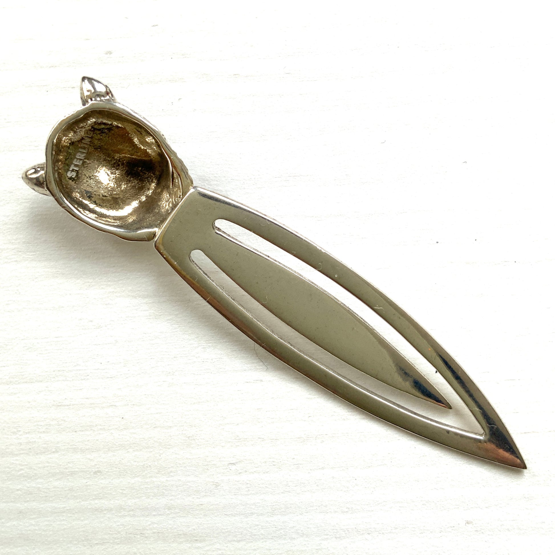 A cute cat's head peeks out from your book — a silver bookmark with a touch of charm.  かわいい猫の頭が本からのぞく、シルバー製のブックマーク。