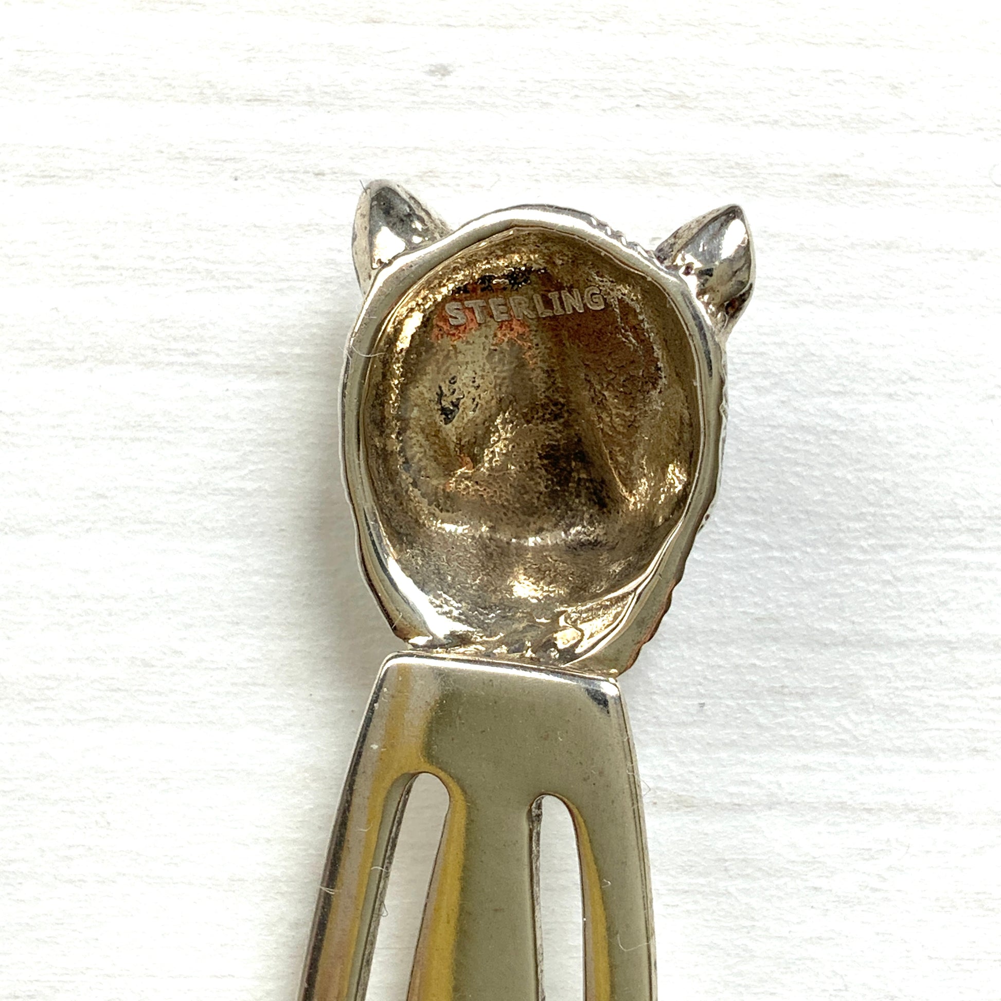 A cute cat's head peeks out from your book — a silver bookmark with a touch of charm.  かわいい猫の頭が本からのぞく、シルバー製のブックマーク。