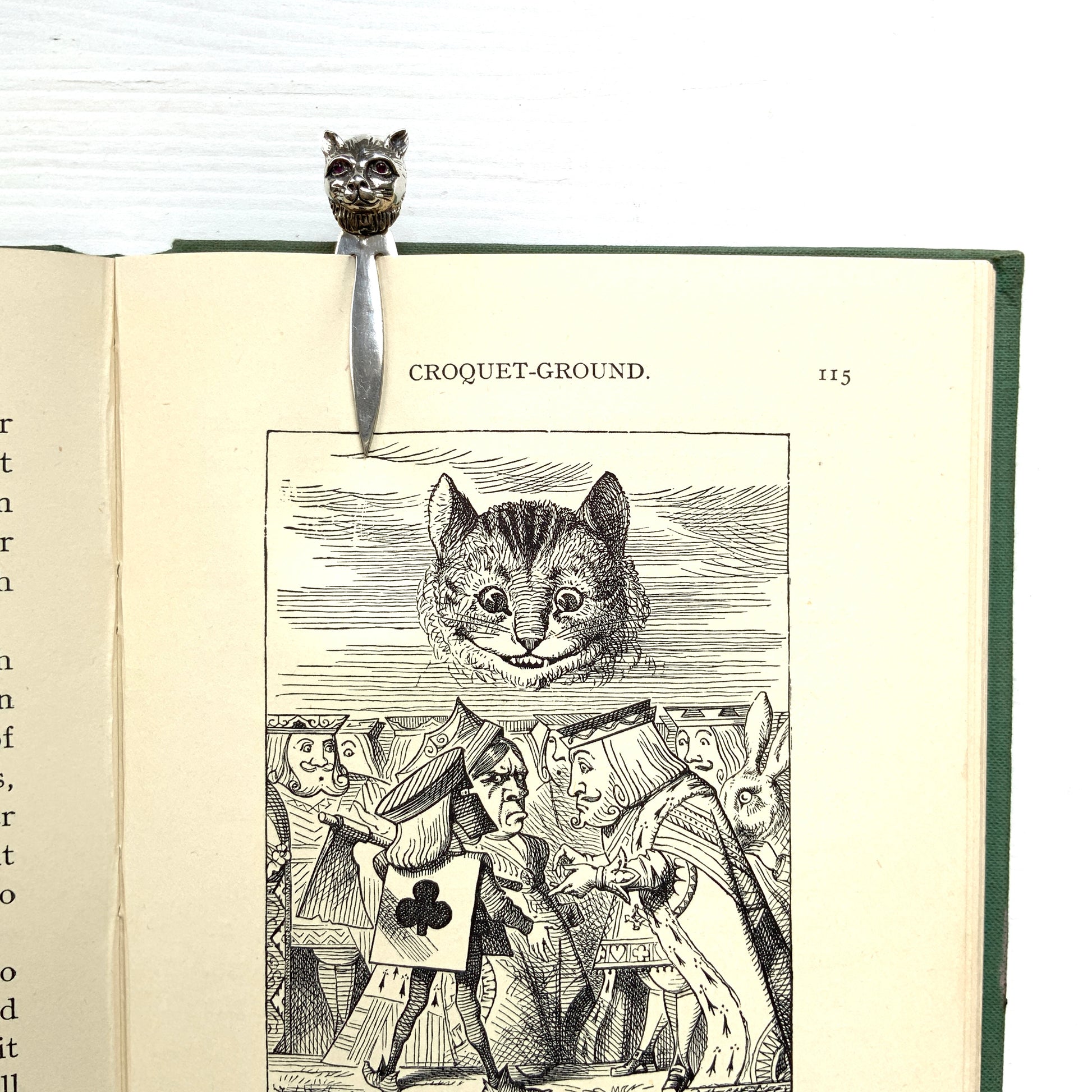 A cute cat's head peeks out from your book — a silver bookmark with a touch of charm.  かわいい猫の頭が本からのぞく、シルバー製のブックマーク。