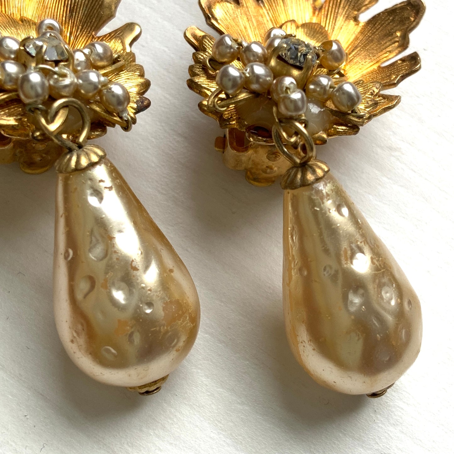 Clip-on earrings featuring gold-tone leaves, tiny pearl flowers, and dangling teardrop glass pearls. ゴールドトーンの美しいリーフに小粒パールのお花と、ティアドロップのグラスパールがゆれるクリップイヤリング。