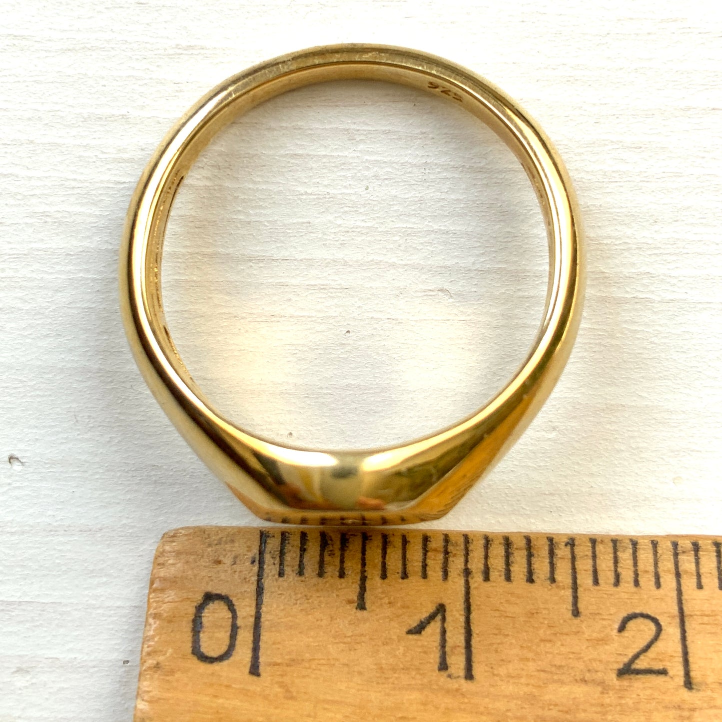A gold-plated silver ring featuring an oval signet with a single clear stone sparkling at the centre. 楕円のシグネットにクリアストーンが一粒きらりと輝く金メッキされたシルバーリング。