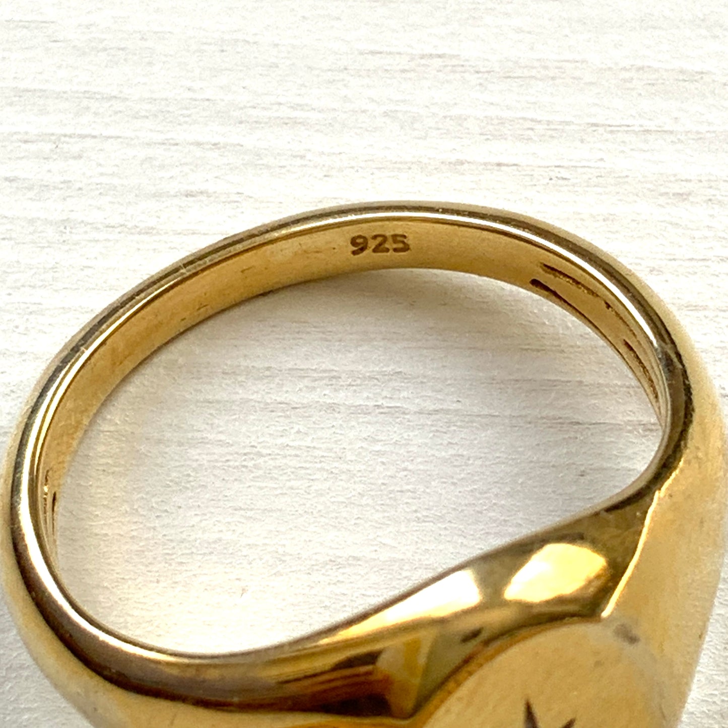 A gold-plated silver ring featuring an oval signet with a single clear stone sparkling at the centre. 楕円のシグネットにクリアストーンが一粒きらりと輝く金メッキされたシルバーリング。