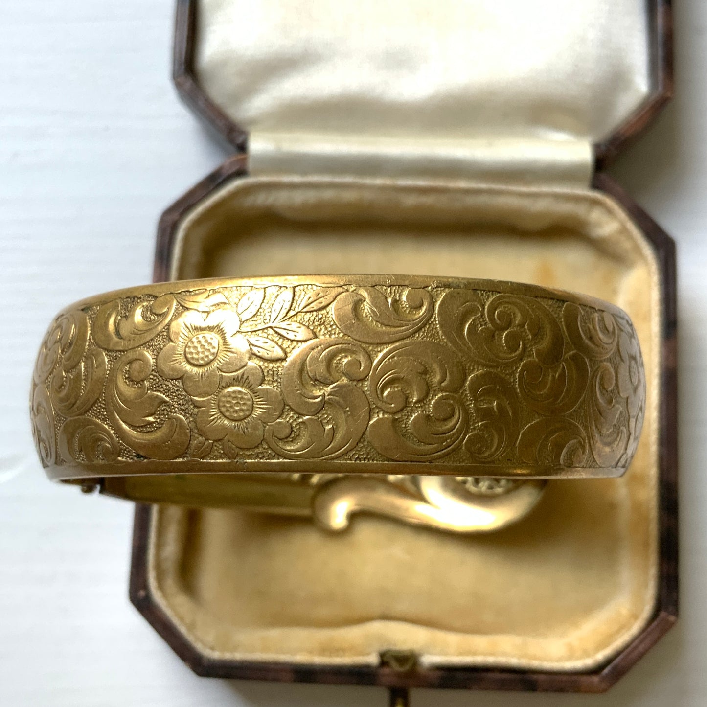 This gold-tone metal bangle features an elegant buckle adorned with delicate filigree work.  フィリグリーで装飾されたエレガントなバックルが印象的なゴールドトーンメタルのバングル。