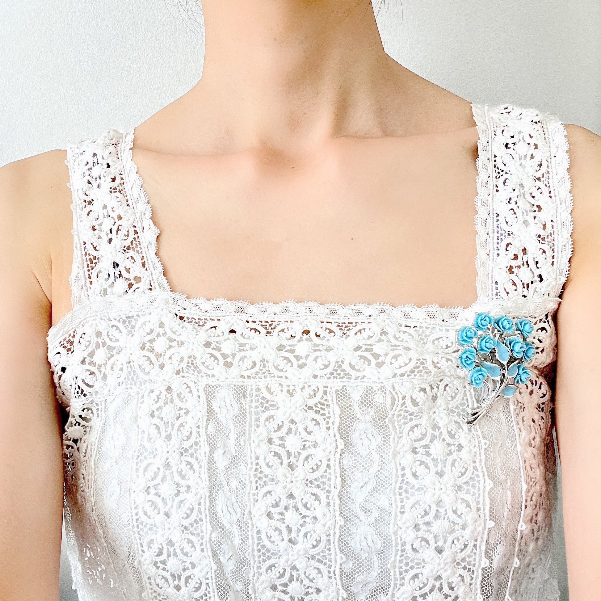 A bouquet brooch featuring sky blue plastic roses, with matching enamel-coated leaves and silver-tone branches that beautifully complement the color scheme. 空色のプラスチックのバラのブーケブローチ。