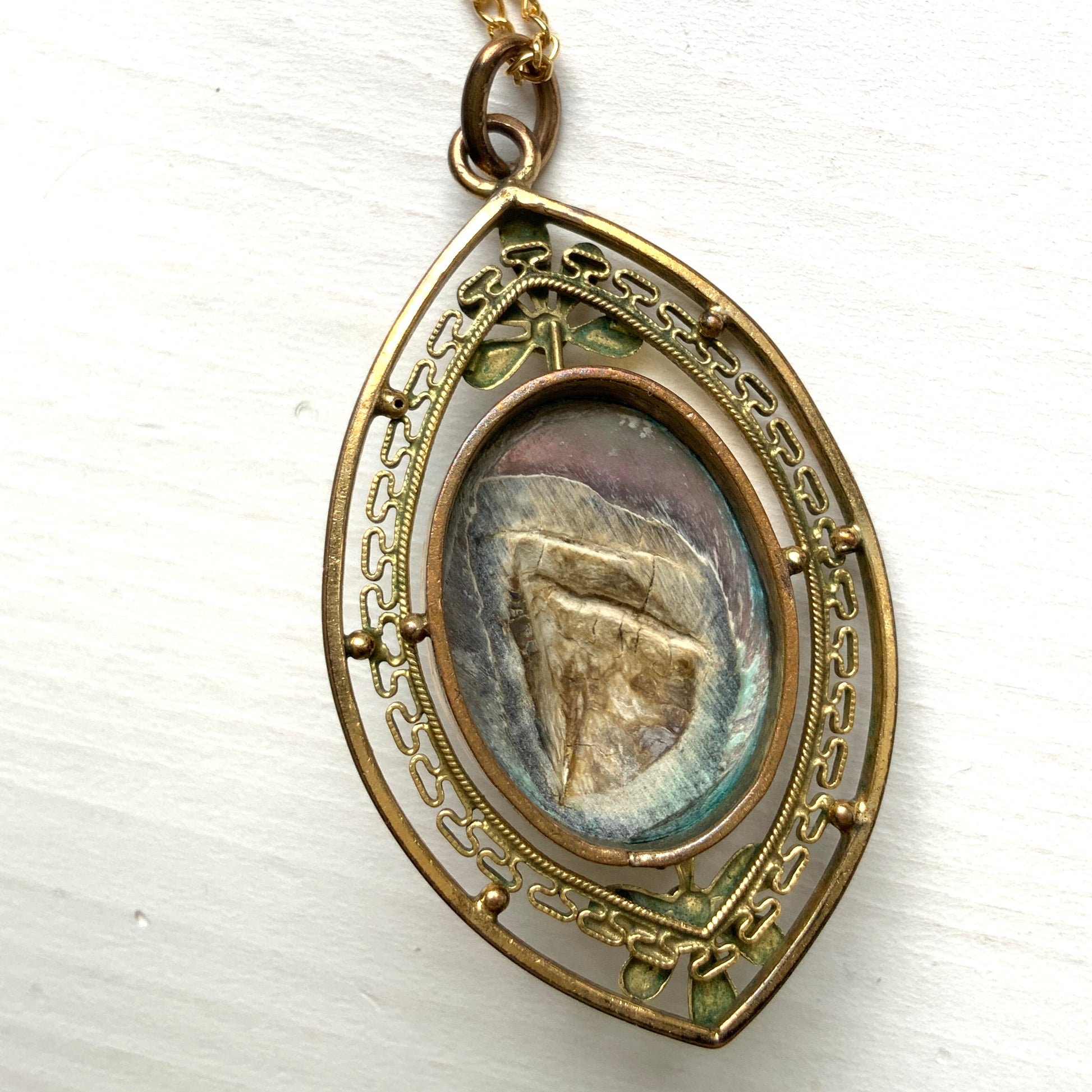 A pendant necklace featuring a large silver-coloured mabe pearl and gold-tone filigree.  大きなシルバーカラーのマベパール と、ゴールドトーンのフィリグリーのペンダントネックレス。