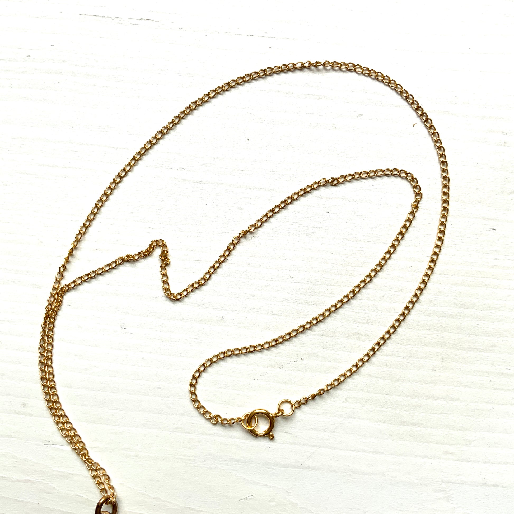 A pendant necklace featuring a large silver-coloured mabe pearl and gold-tone filigree.  大きなシルバーカラーのマベパール と、ゴールドトーンのフィリグリーのペンダントネックレス。