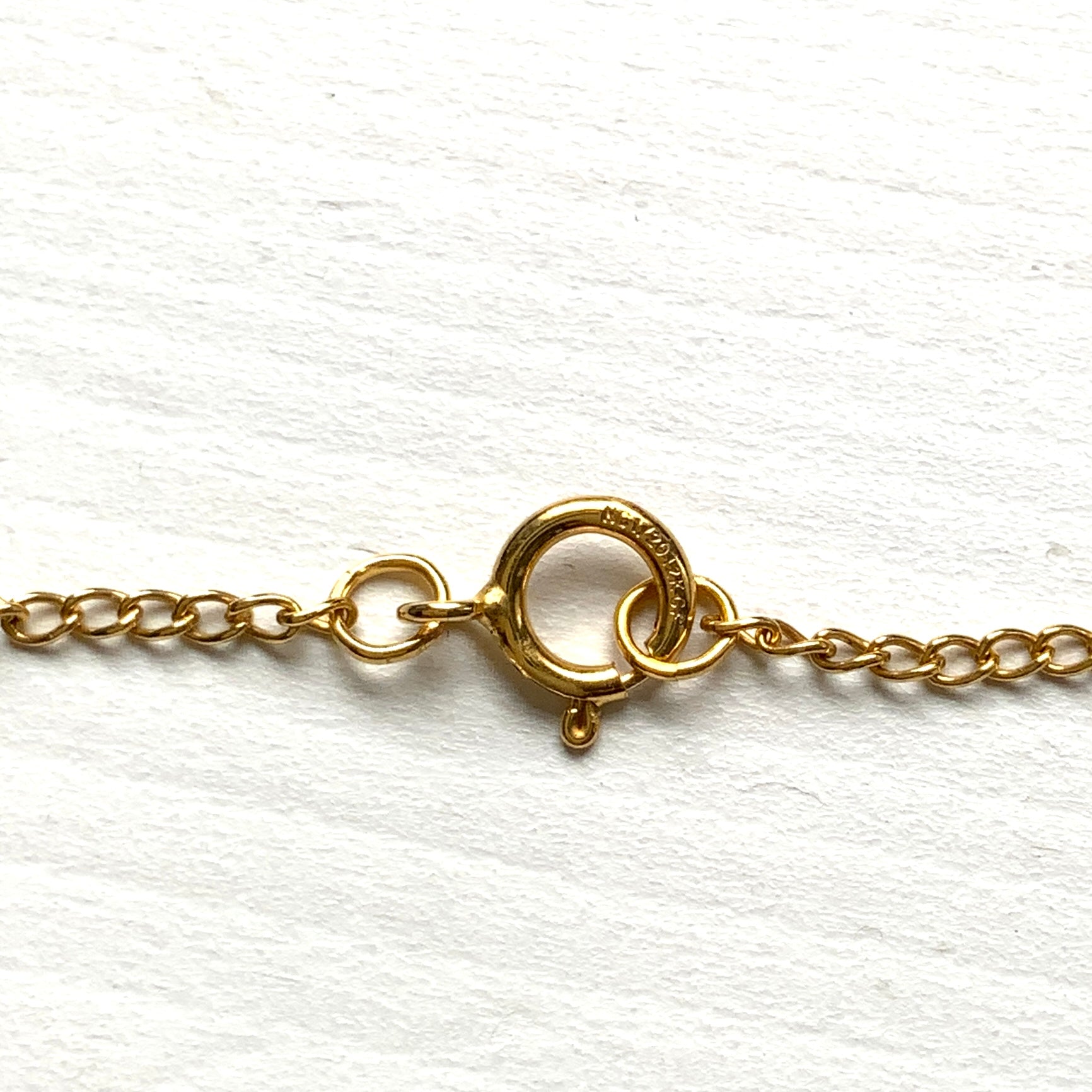 A pendant necklace featuring a large silver-coloured mabe pearl and gold-tone filigree.  大きなシルバーカラーのマベパール と、ゴールドトーンのフィリグリーのペンダントネックレス。