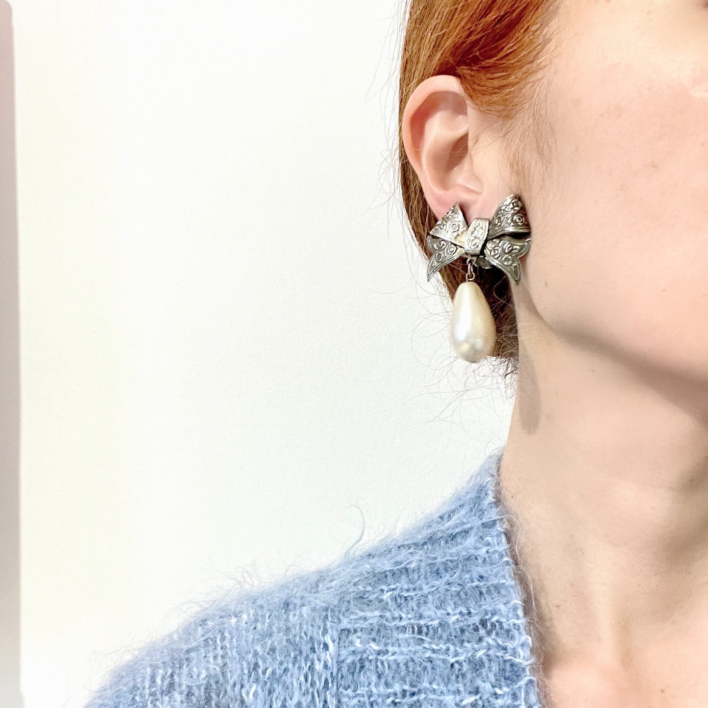 Vintage clip-on earrings featuring a silver-tone bow with large teardrop pearls that gently sway. シルバートーンメタルのリボンに、大きなティアドロップパールが揺れるクリップイヤリング。