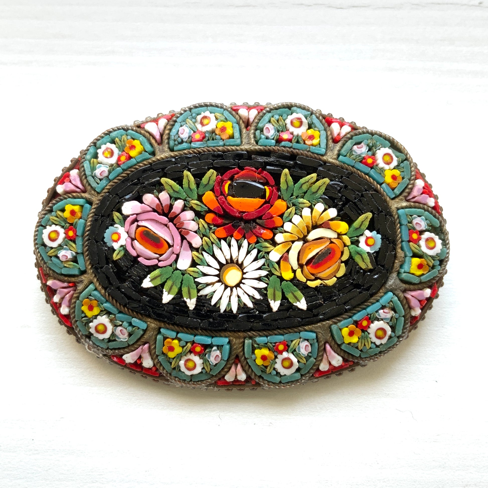 A vibrant and colorful oval micro mosaic brooch featuring a striking floral design.鮮やかでカラフルなお花のマイクロモザイク のオーバル型ブローチ。