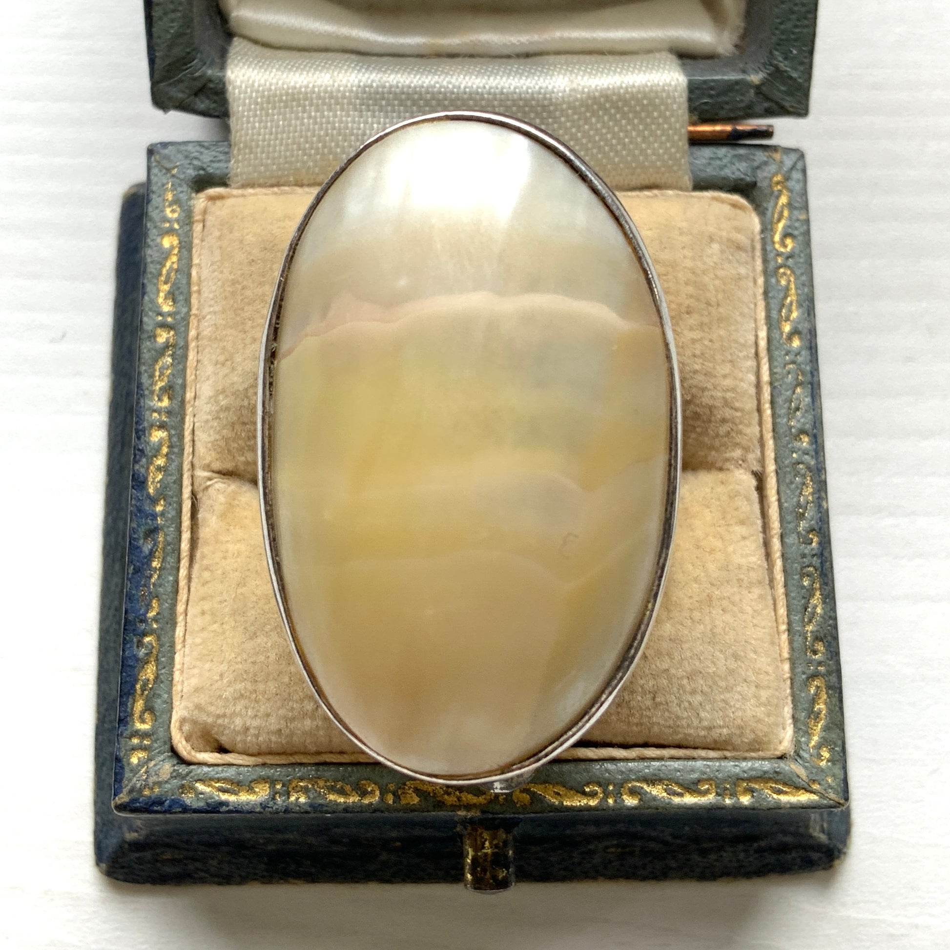 A silver ring featuring an oval domed piece of ivory-colored mother of pearl. アイボリーカラーのマザーオブパールをあしらった、オーバル型ドームのシルバーリング。