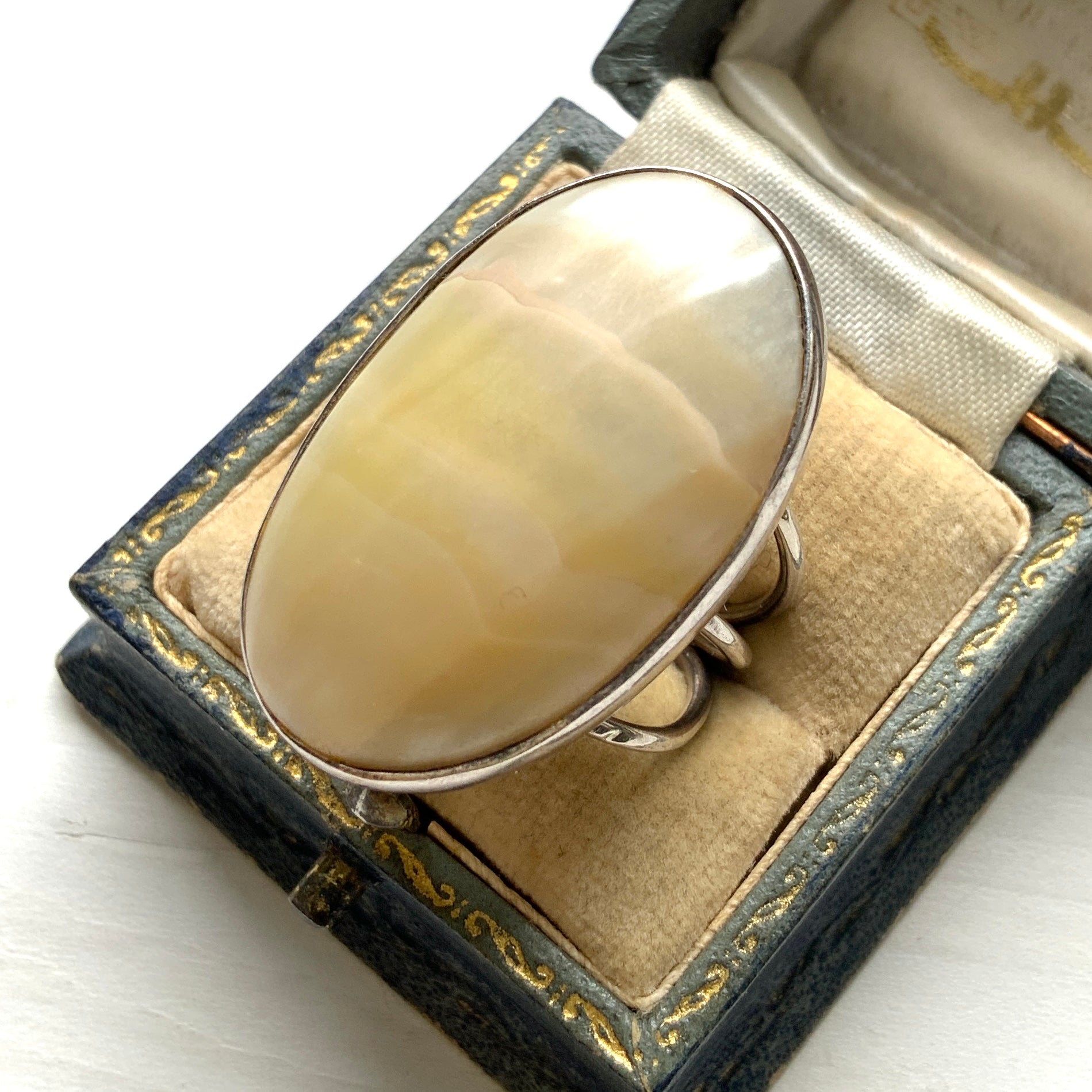 A silver ring featuring an oval domed piece of ivory-colored mother of pearl. アイボリーカラーのマザーオブパールをあしらった、オーバル型ドームのシルバーリング。