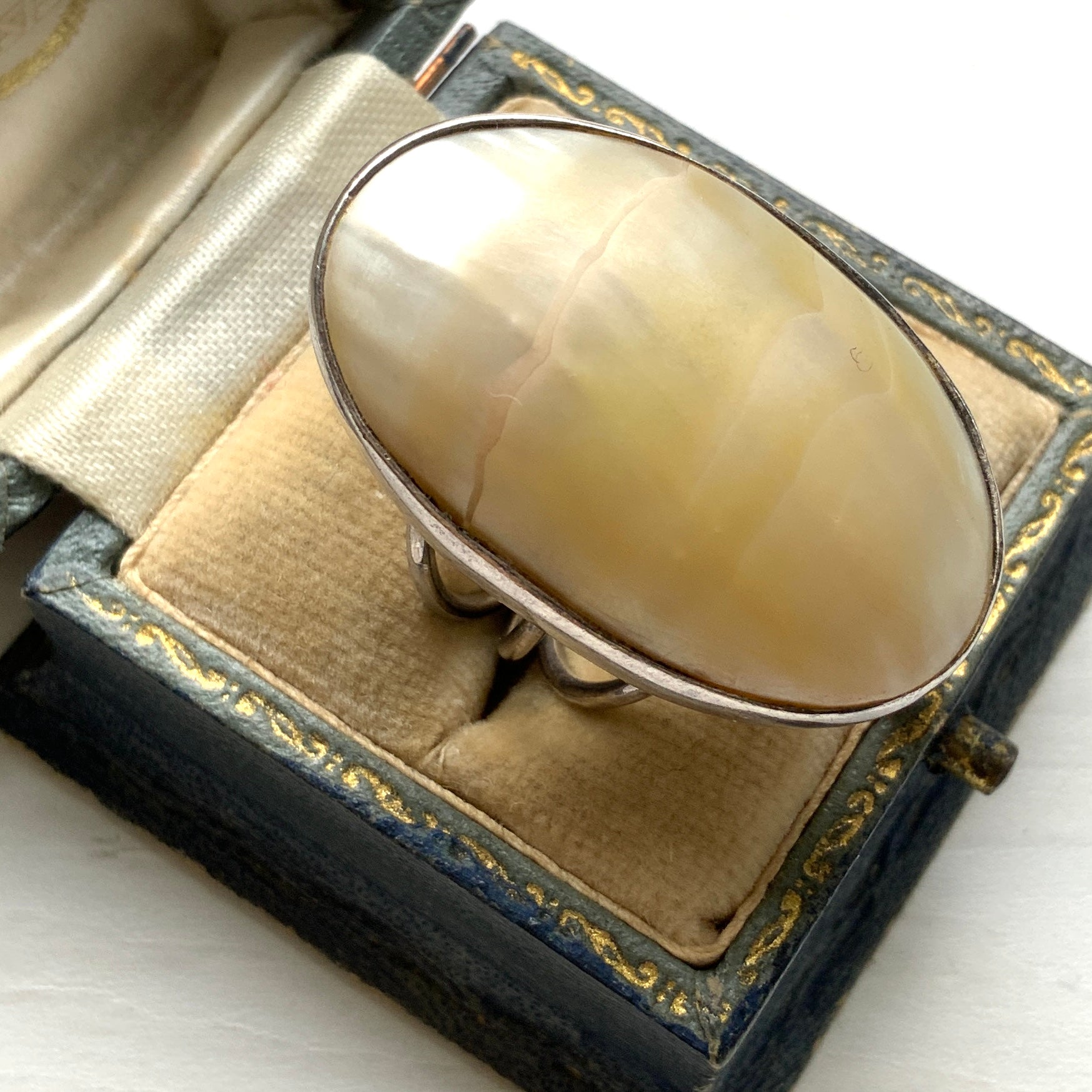 A silver ring featuring an oval domed piece of ivory-colored mother of pearl. アイボリーカラーのマザーオブパールをあしらった、オーバル型ドームのシルバーリング。