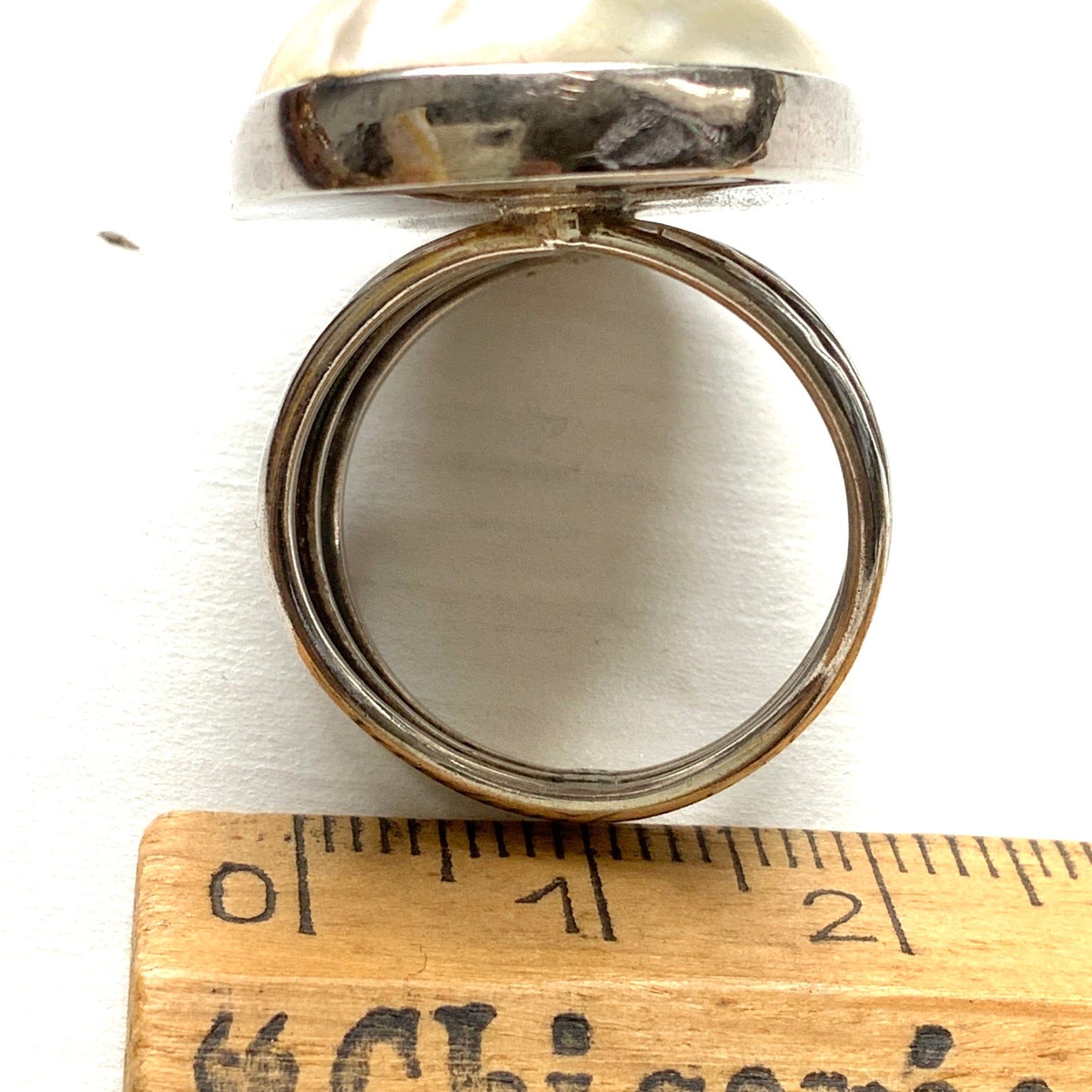 A silver ring featuring an oval domed piece of ivory-colored mother of pearl. アイボリーカラーのマザーオブパールをあしらった、オーバル型ドームのシルバーリング。
