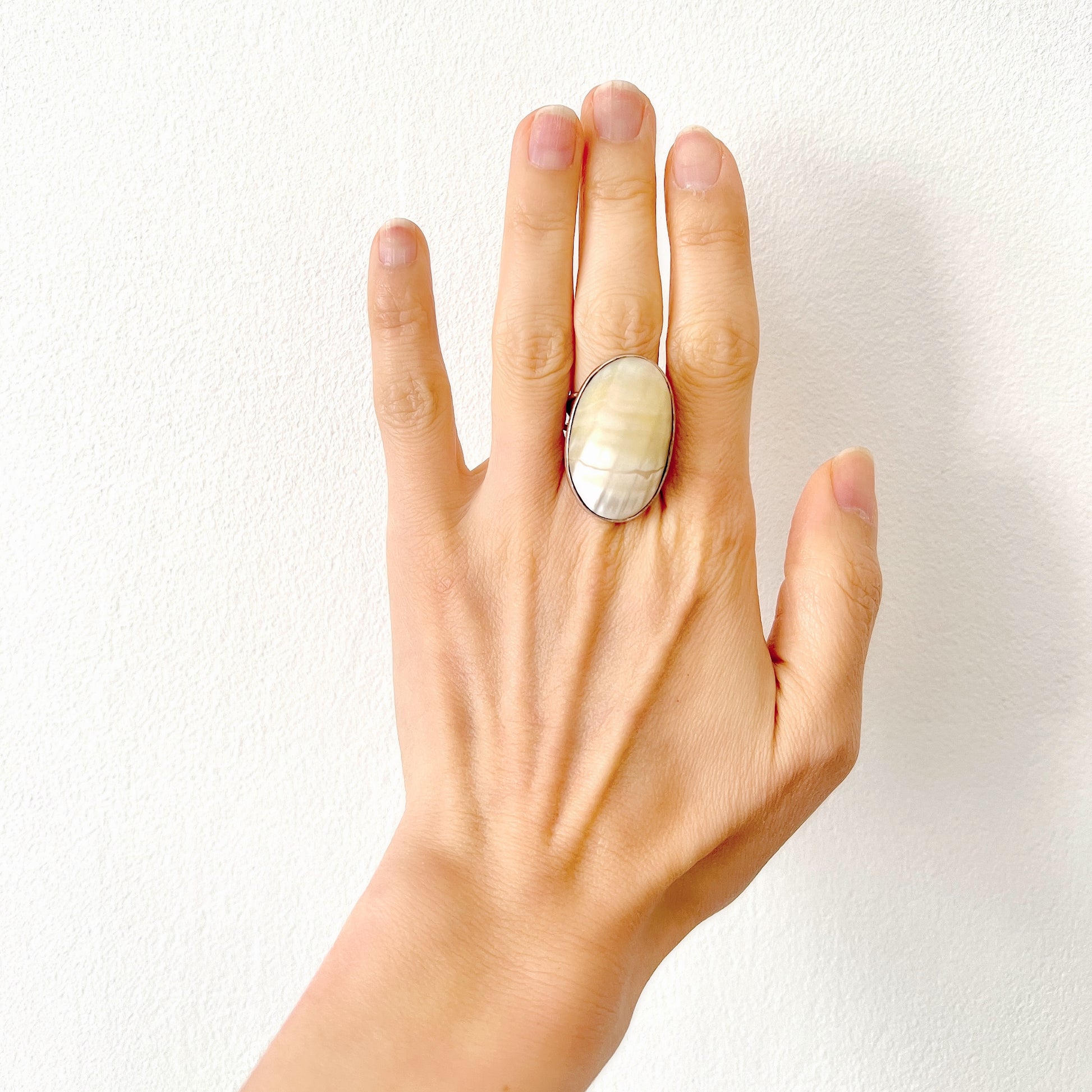 A silver ring featuring an oval domed piece of ivory-colored mother of pearl. アイボリーカラーのマザーオブパールをあしらった、オーバル型ドームのシルバーリング。