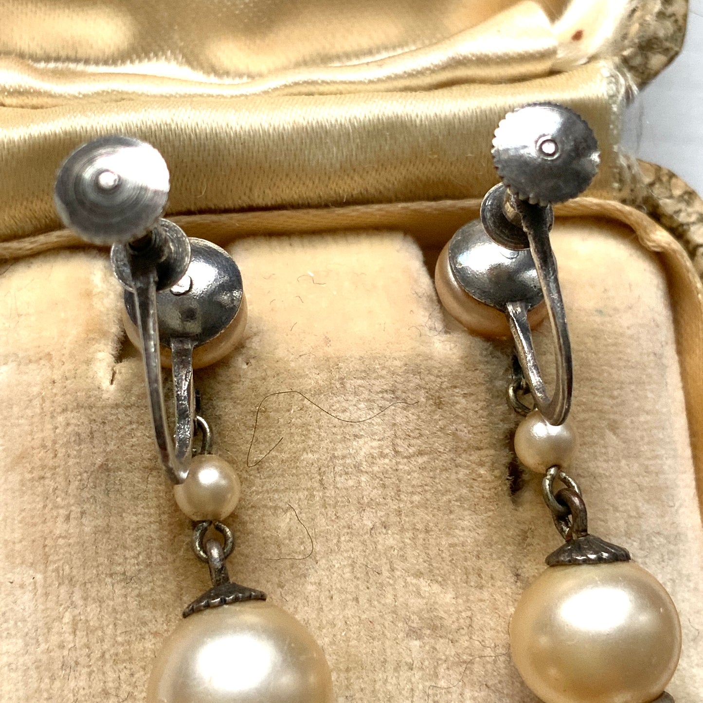 Cream-coloured glass pearls dangle from these screw-back earrings. クリームカラーのグラスパールがゆれるスクリューイヤリング。