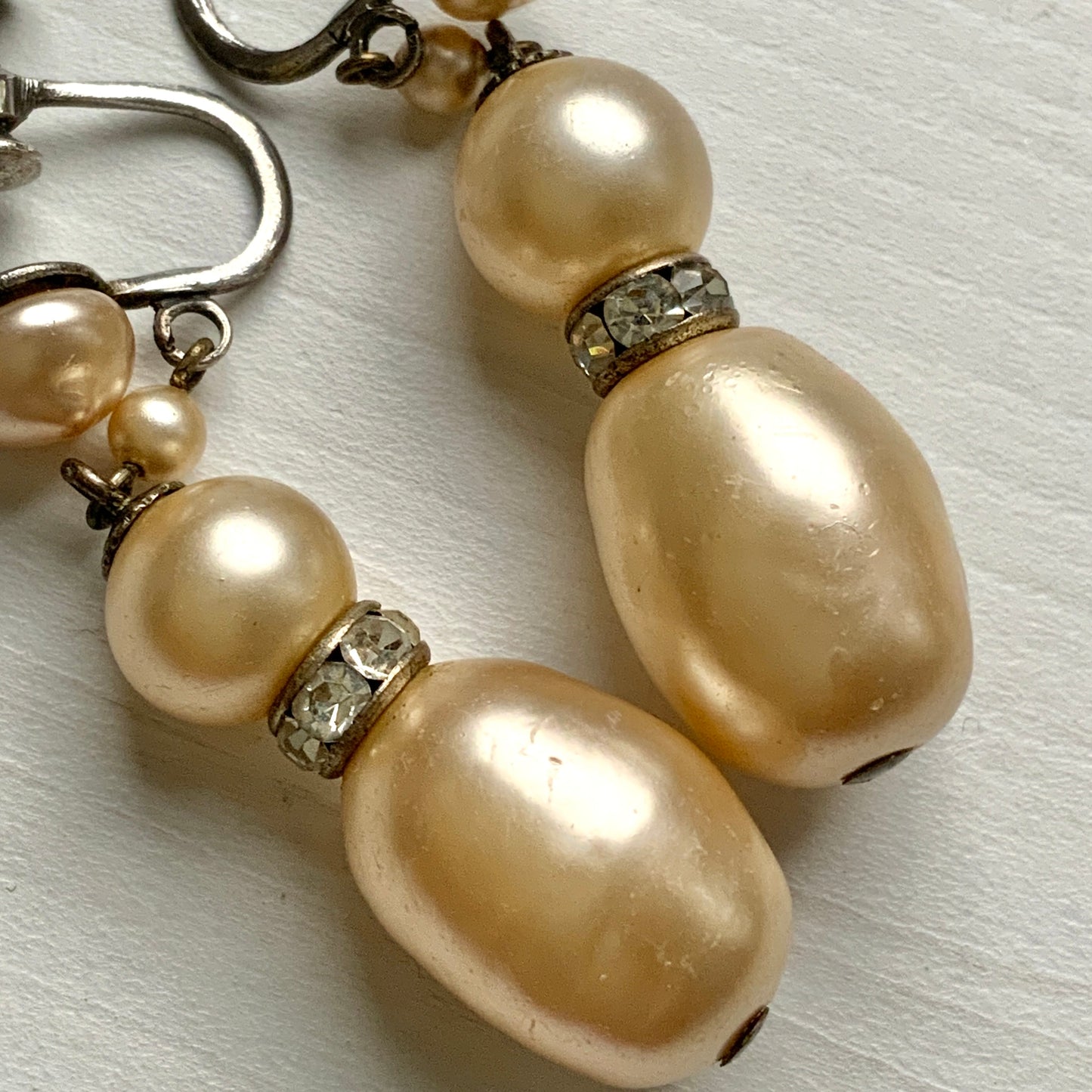 Cream-coloured glass pearls dangle from these screw-back earrings. クリームカラーのグラスパールがゆれるスクリューイヤリング。