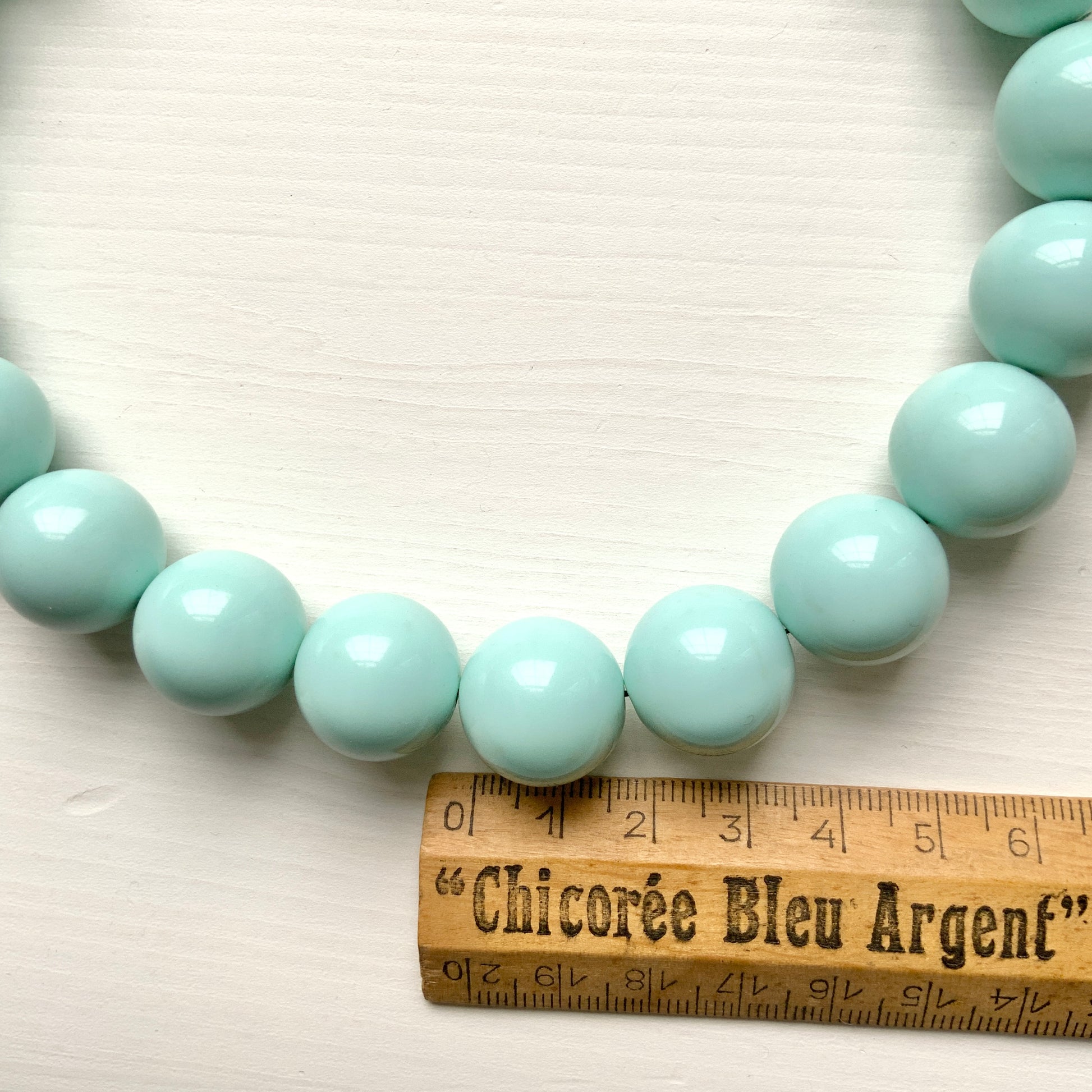 A choker necklace with large ice blue plastic beads, adding a subtle pop of cool color around the neck.  さわやかなアイスブルーのプラスチックビーズ のチョーカーネックレス。