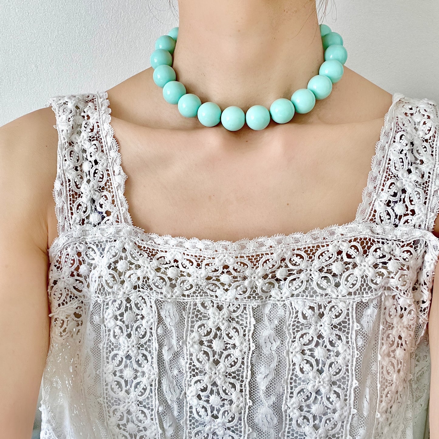 A choker necklace with large ice blue plastic beads, adding a subtle pop of cool color around the neck. さわやかなアイスブルーのプラスチックビーズ のチョーカーネックレス。
