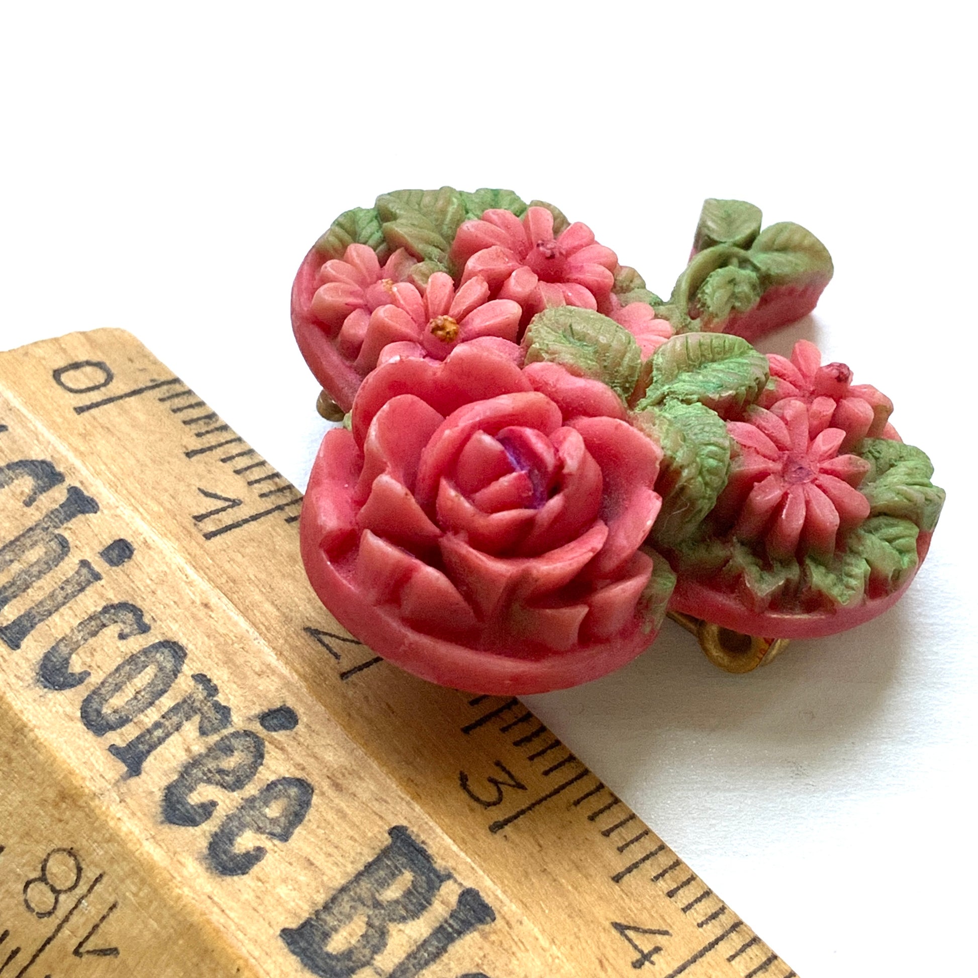 A brooch featuring a three-leaf clover motif, adorned with red roses and daisy flowers shaped into the design. 三つ葉クローバーのモチーフに、赤いバラやデイジーのお花が象られたブローチ。