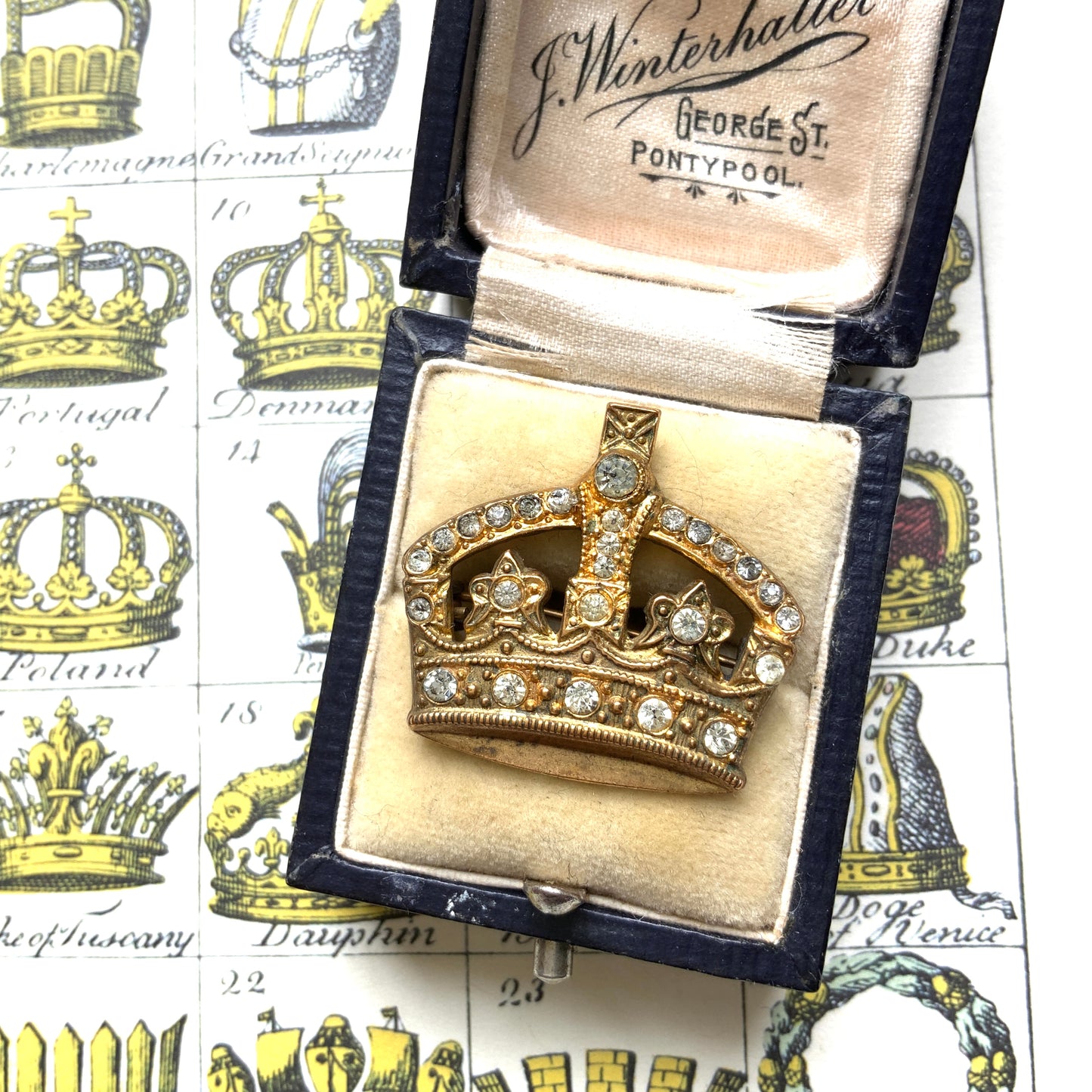 A gold-tone metal crown brooch adorned with clear rhinestones. ゴールドトーンメタルのクラウンに、クリアラインストーンがあしらわれたブローチ。