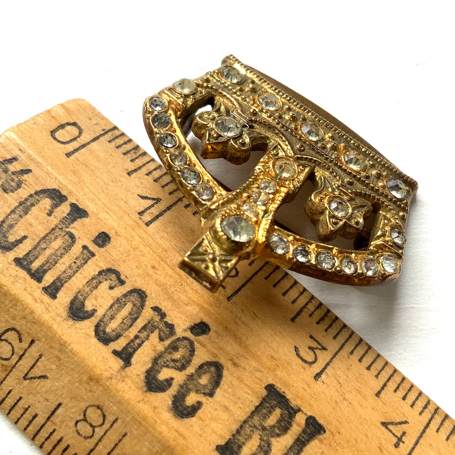 A gold-tone metal crown brooch adorned with clear rhinestones. ゴールドトーンメタルのクラウンに、クリアラインストーンがあしらわれたブローチ。