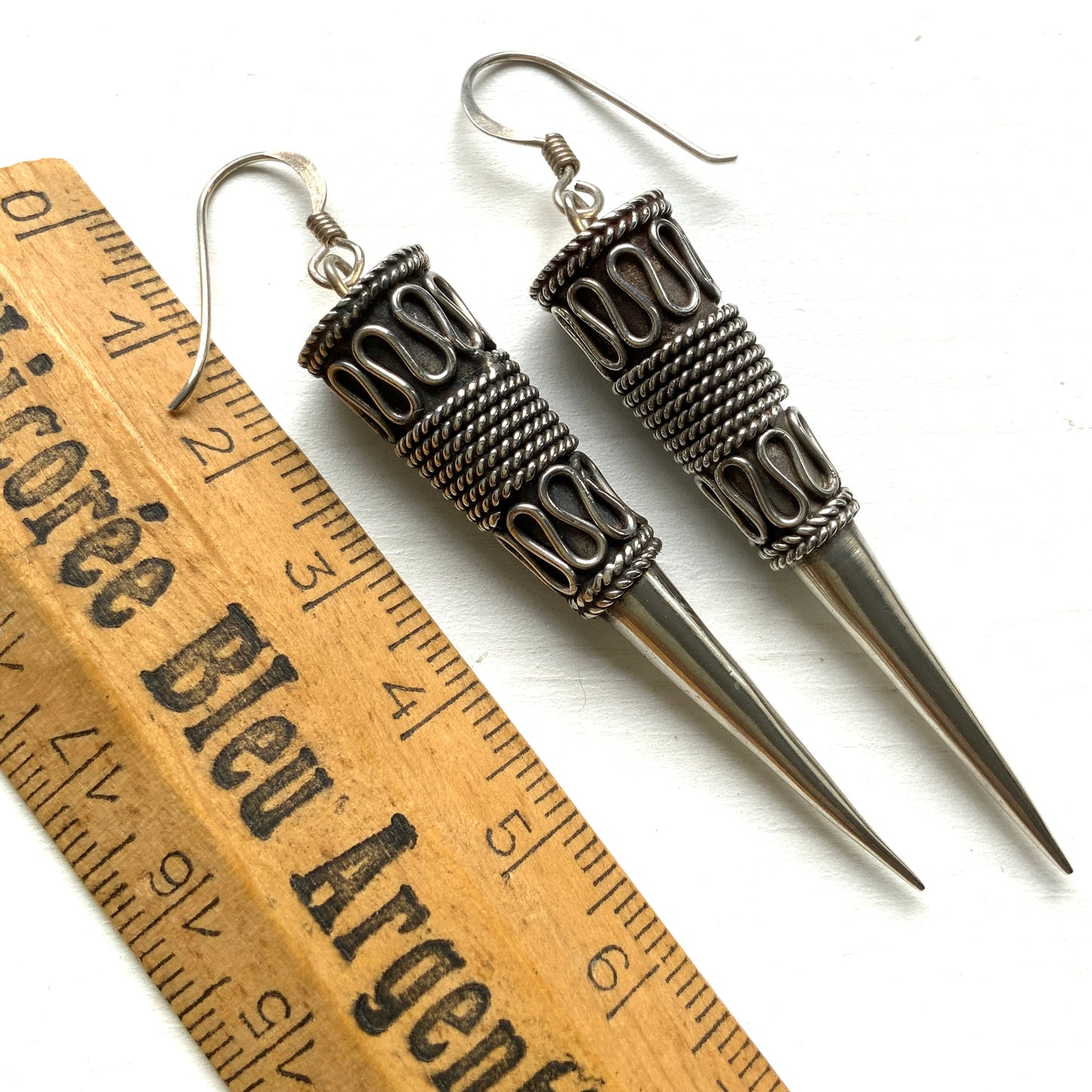 Silver spike-shaped earrings with tribal-inspired patterns. トライバルな模様が入った細長いスパイク型のシルバーピアス。