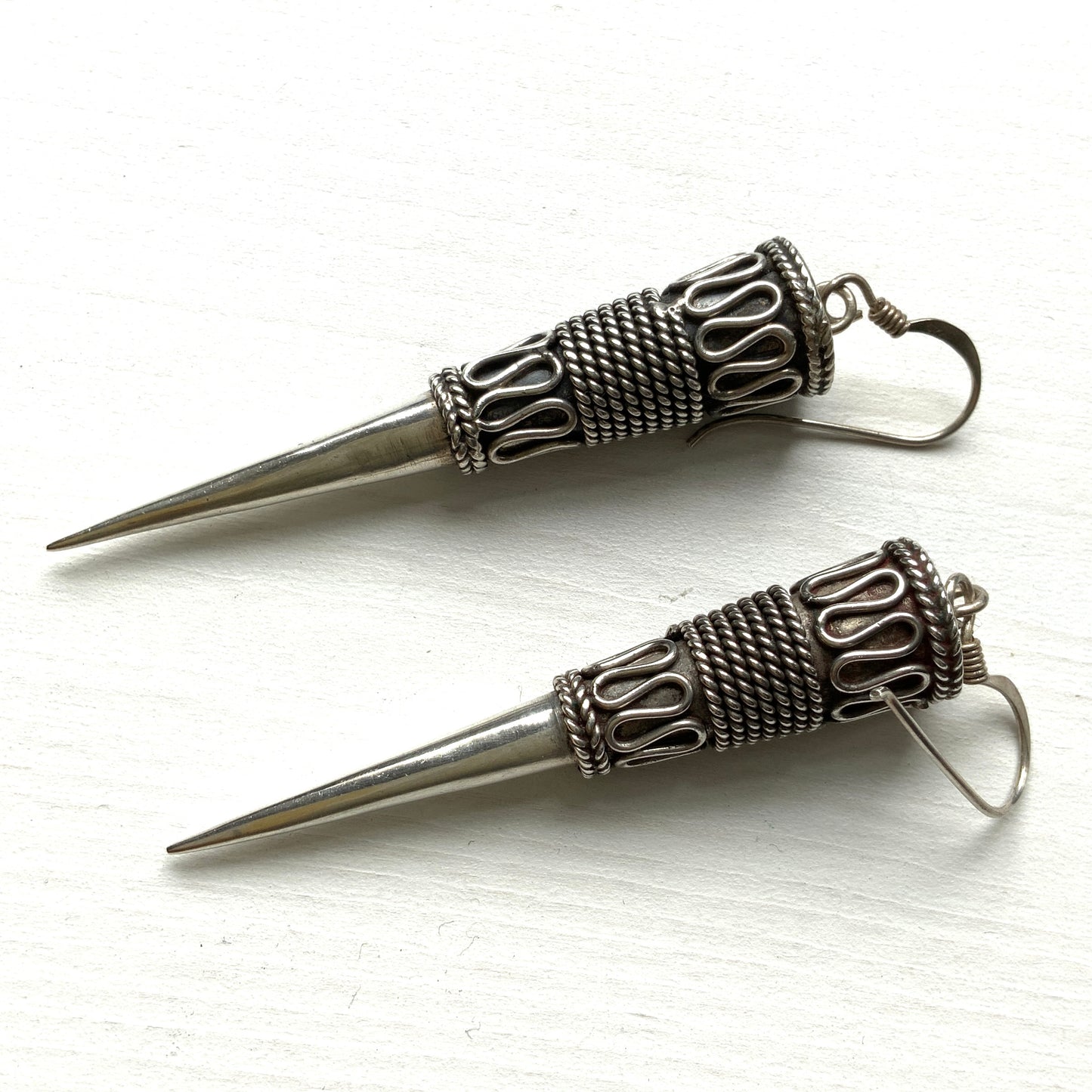 Silver spike-shaped earrings with tribal-inspired patterns. トライバルな模様が入った細長いスパイク型のシルバーピアス。