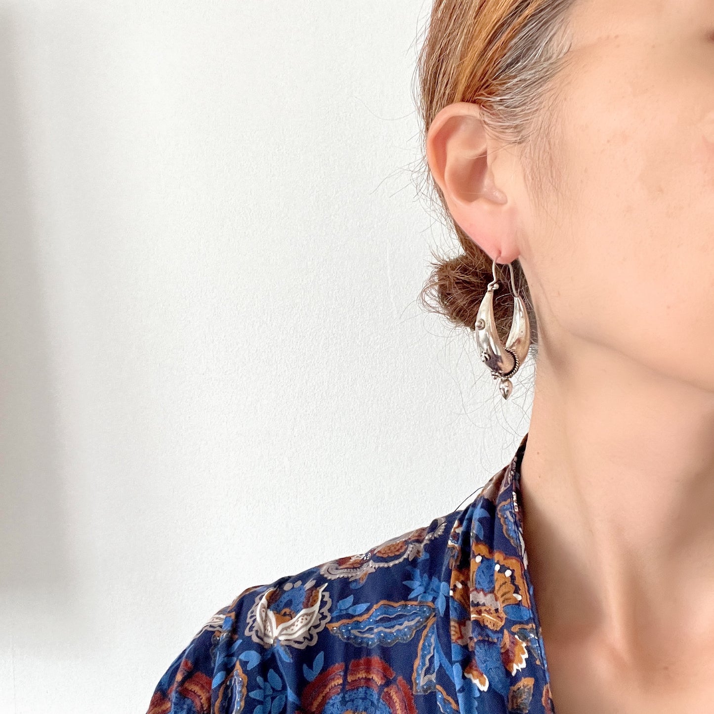 Bold silver hoop earrings in a crescent form, decorated with granulated details and teardrop-shaped protrusions. 三日月型に粒状の装飾とドロップ状の突起をあしらった存在感のあるシルバーフープピアス。