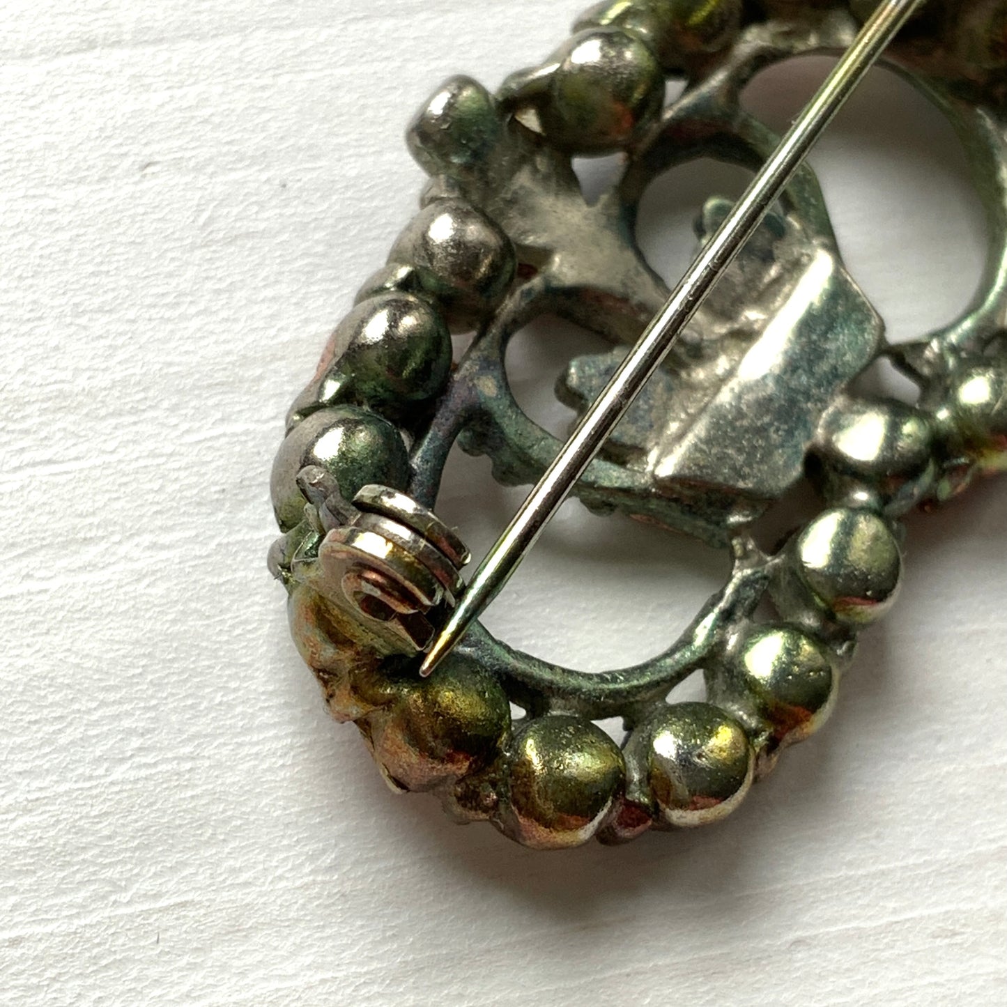 A brooch featuring a crown encircled by tricolour rhinestones – red, clear and blue. 王冠の周りをトリコロールカラーのラインストーンが囲んだブローチ。