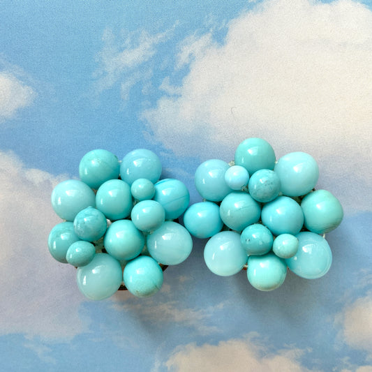 These clip-on earrings feature a charming cluster of turquoise-colored glass beads in various shapes and sizes. いろいろな大きさのターコイズカラーのグラスビーズが集まったクリップイヤリング。