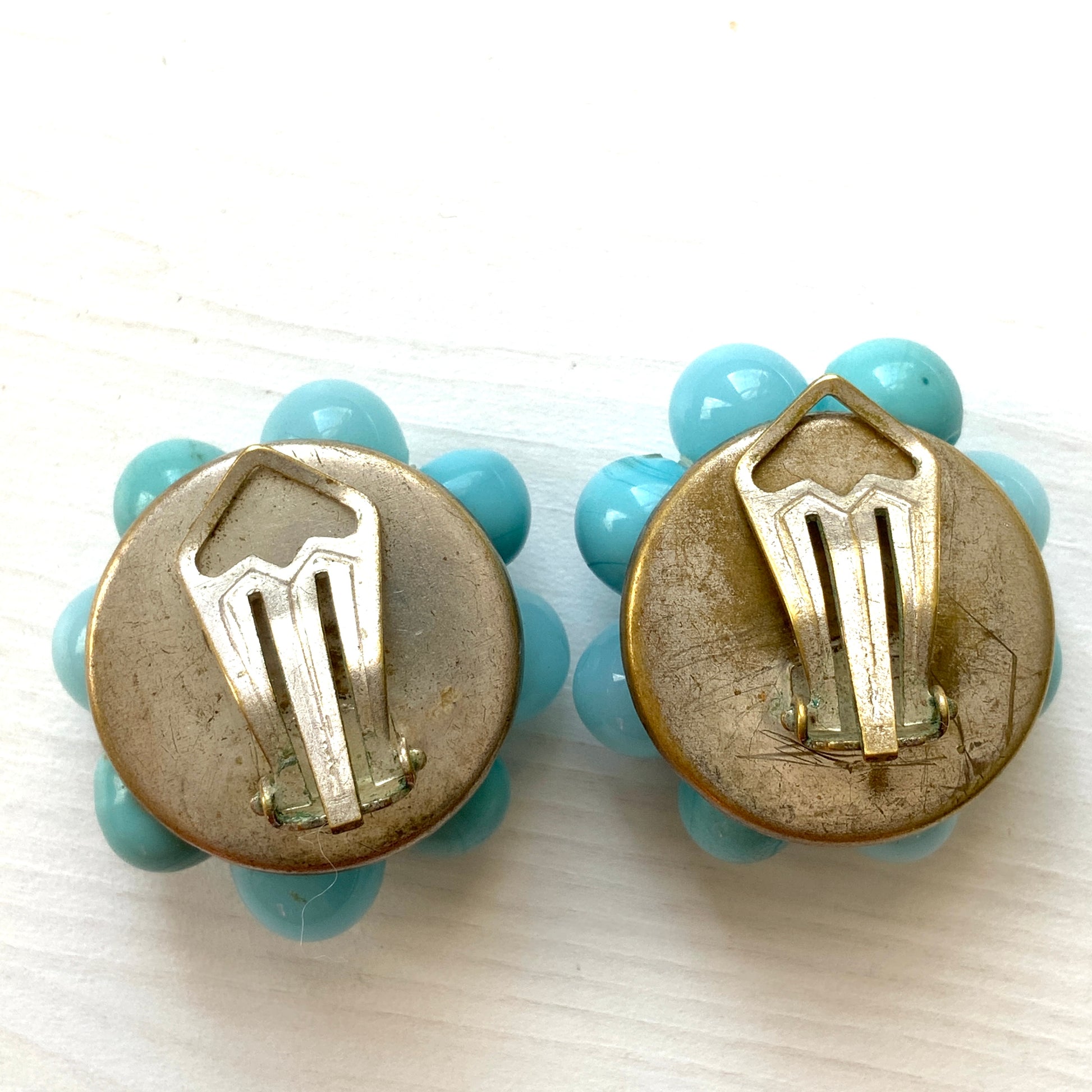 These clip-on earrings feature a charming cluster of turquoise-colored glass beads in various shapes and sizes. いろいろな大きさのターコイズカラーのグラスビーズが集まったクリップイヤリング。