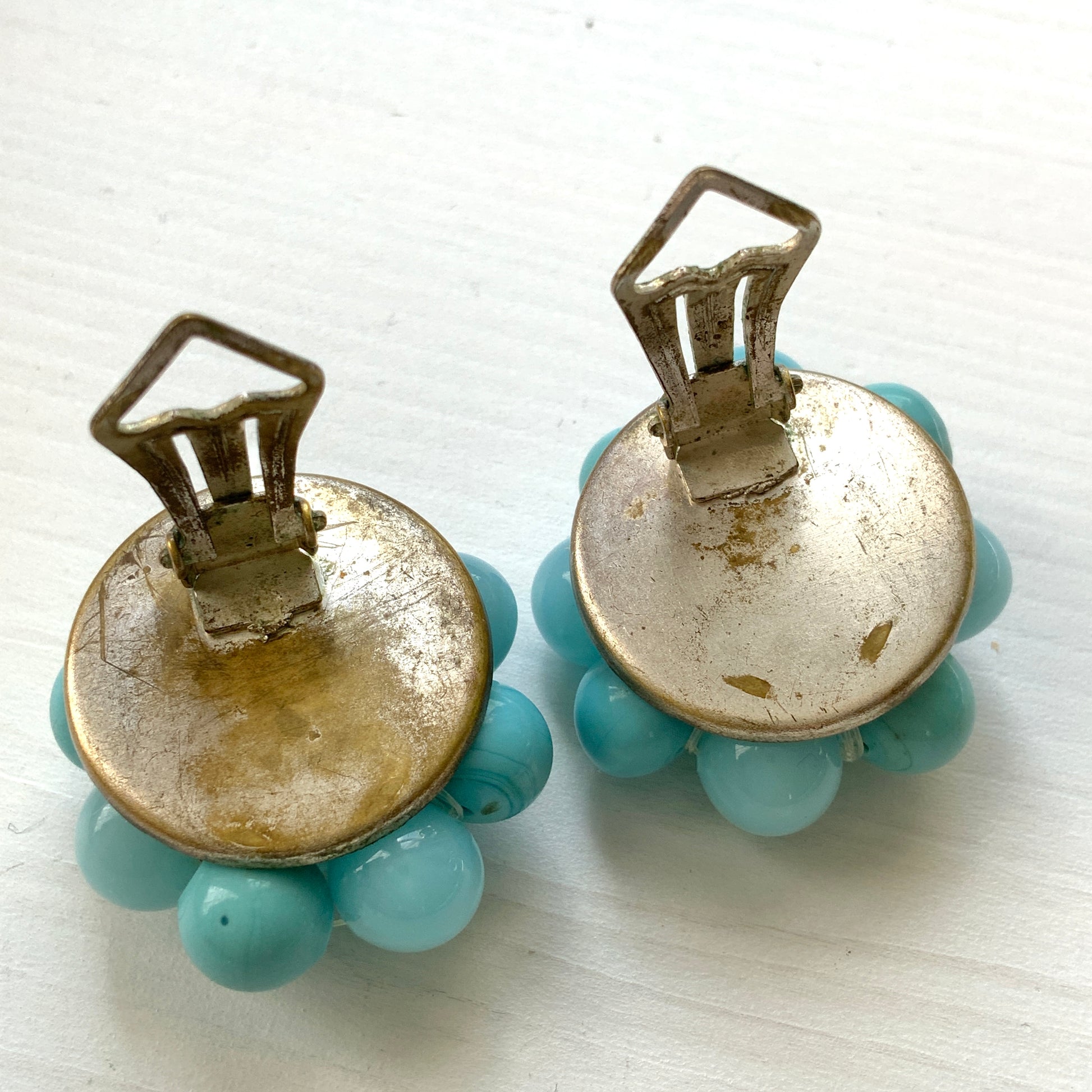 These clip-on earrings feature a charming cluster of turquoise-colored glass beads in various shapes and sizes. いろいろな大きさのターコイズカラーのグラスビーズが集まったクリップイヤリング。