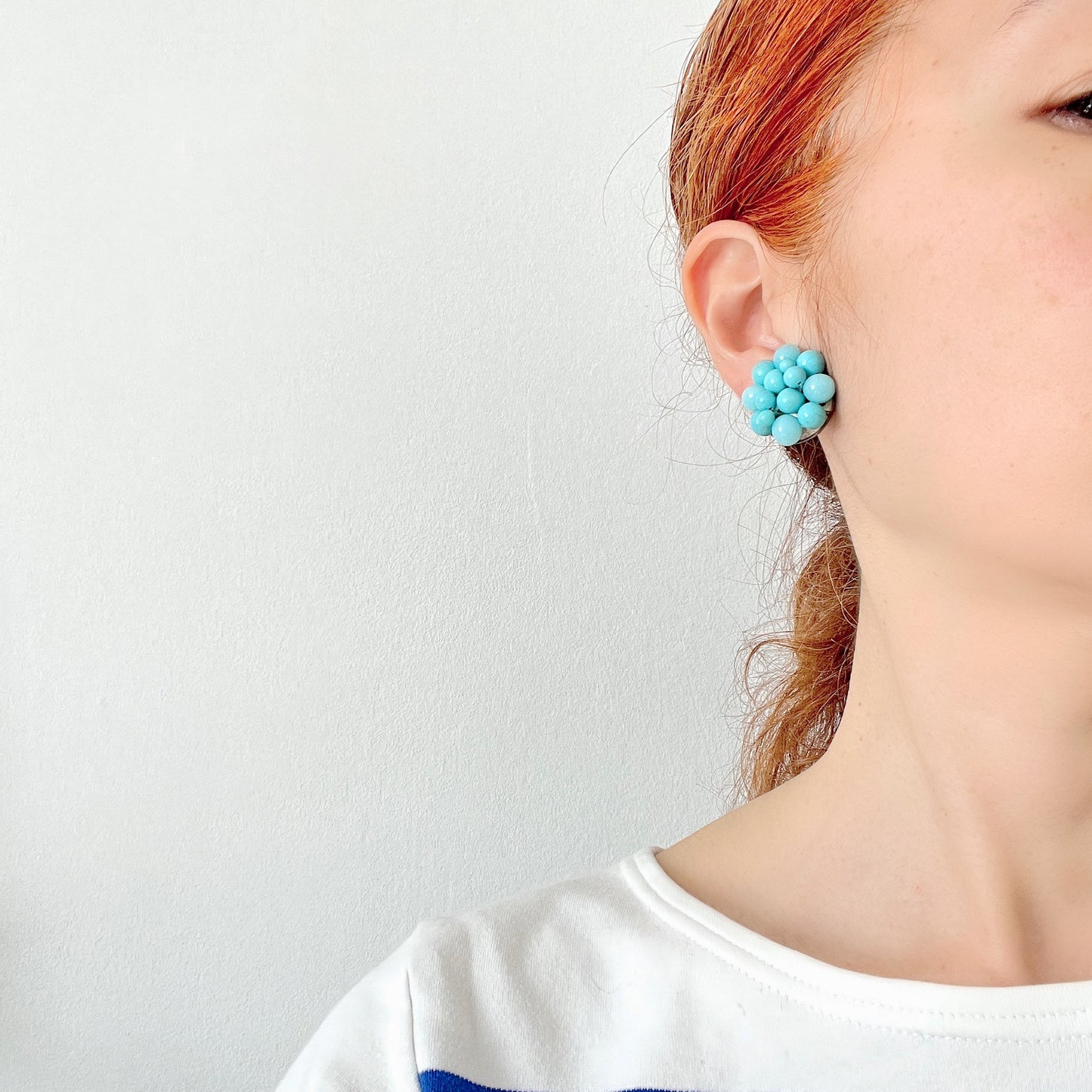 These clip-on earrings feature a charming cluster of turquoise-colored glass beads in various shapes and sizes. いろいろな大きさのターコイズカラーのグラスビーズが集まったクリップイヤリング。
