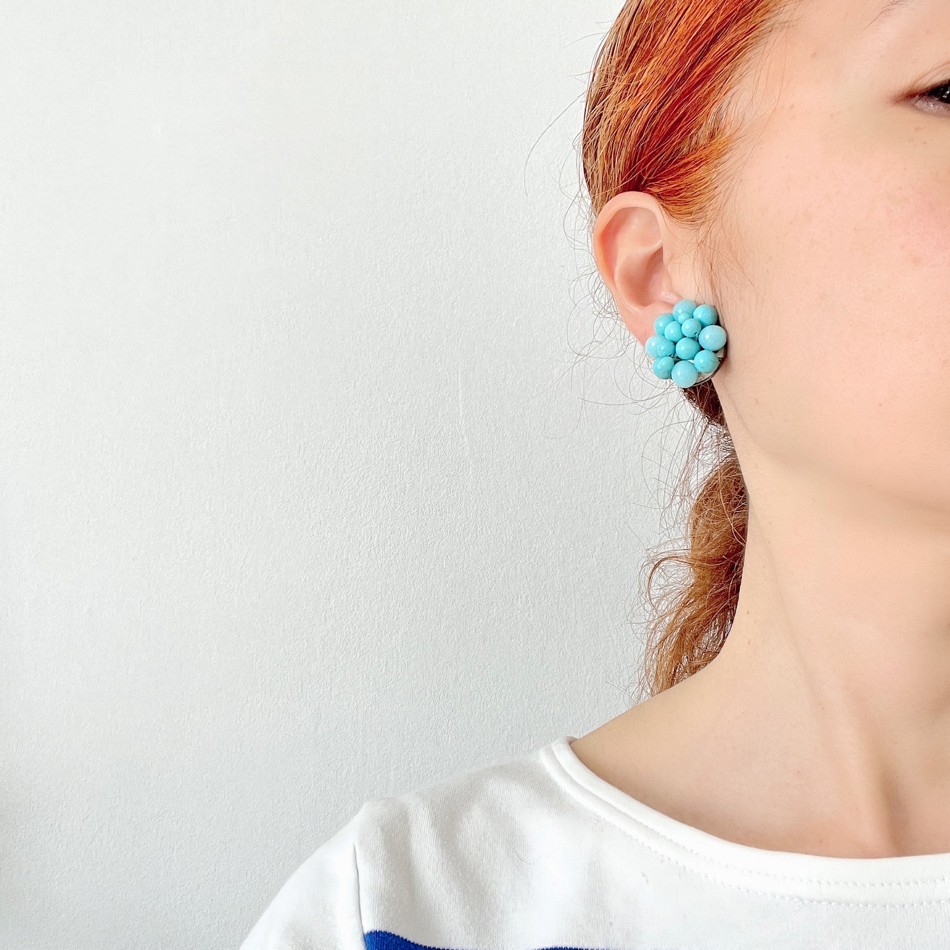 These clip-on earrings feature a charming cluster of turquoise-colored glass beads in various shapes and sizes. いろいろな大きさのターコイズカラーのグラスビーズが集まったクリップイヤリング。