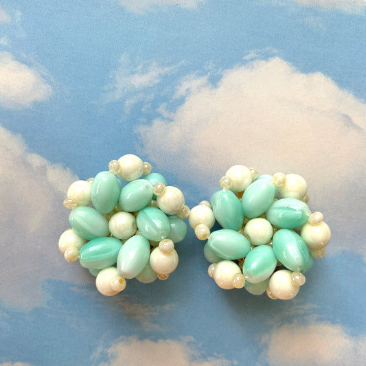 Clip-on earrings featuring floral motifs made from ice blue and white beads. アイスブルーのビーズとホワイトのビーズがお花の形に編まれたクリップイヤリング。
