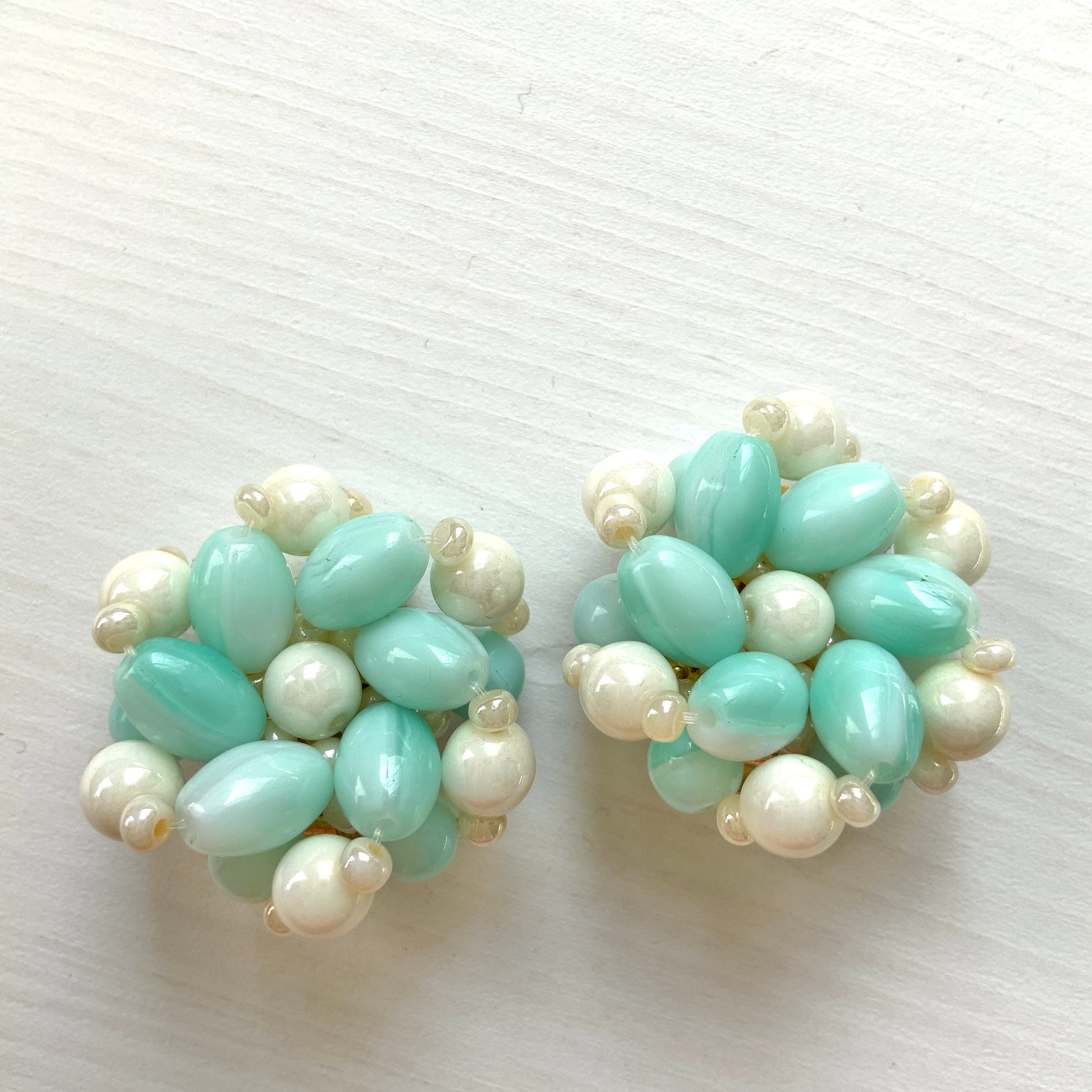 Clip-on earrings featuring floral motifs made from ice blue and white beads. アイスブルーのビーズとホワイトのビーズがお花の形に編まれたクリップイヤリング。
